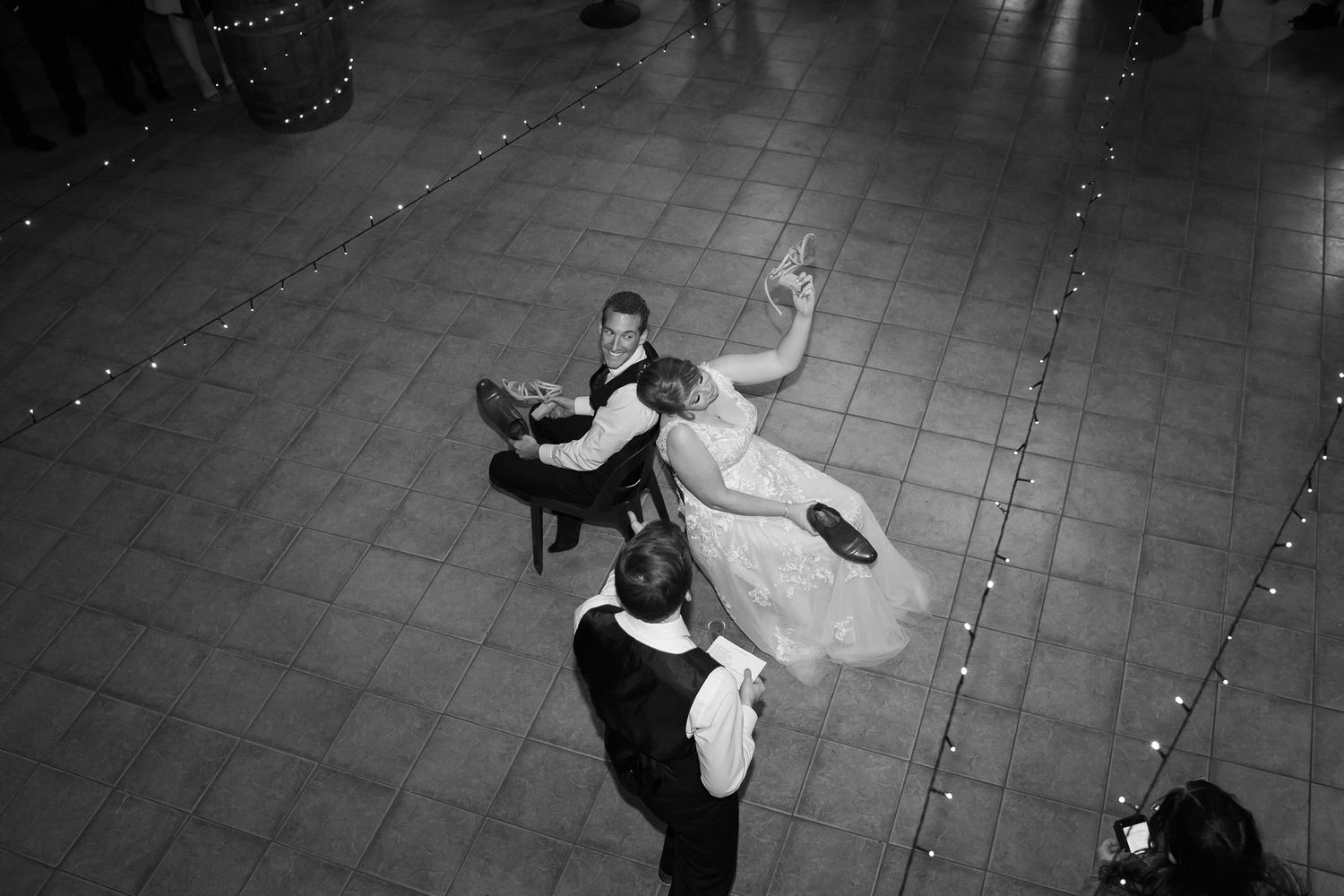 Black and white overhead view of a couple performing an elegant ballroom dance on a tiled floor during a formal event.