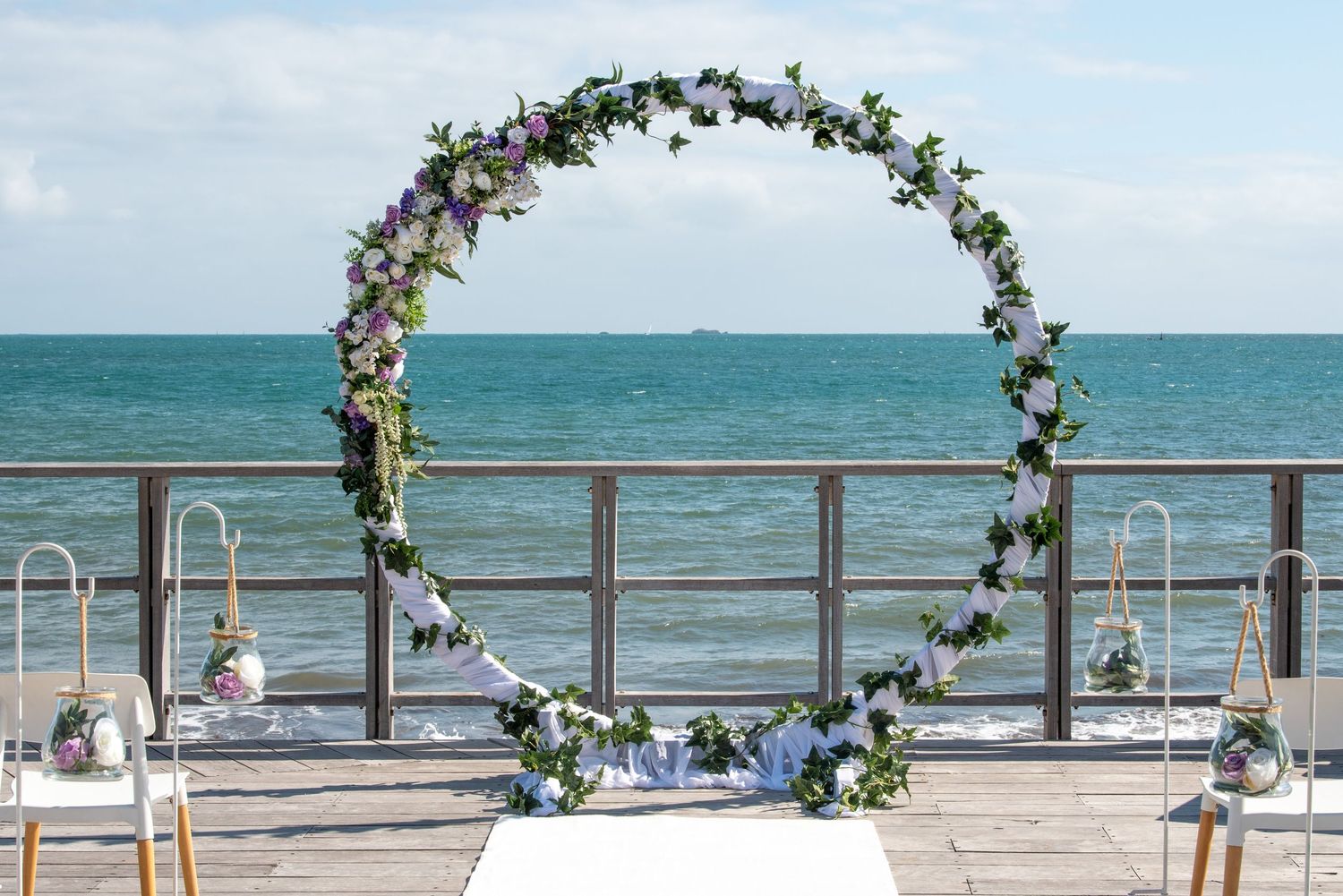 Floral arch stands beautifully against the ocean backdrop at a beachside wedding ceremony setup.