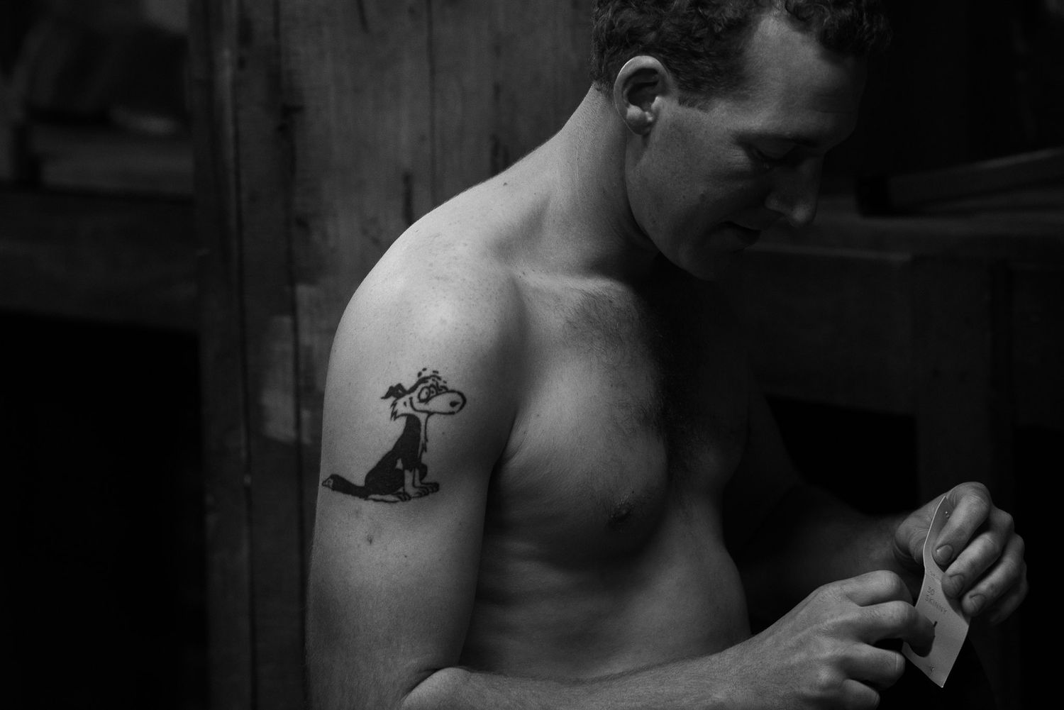 Athletic shirtless boxer trains with focus and intensity in a dark gym setting.