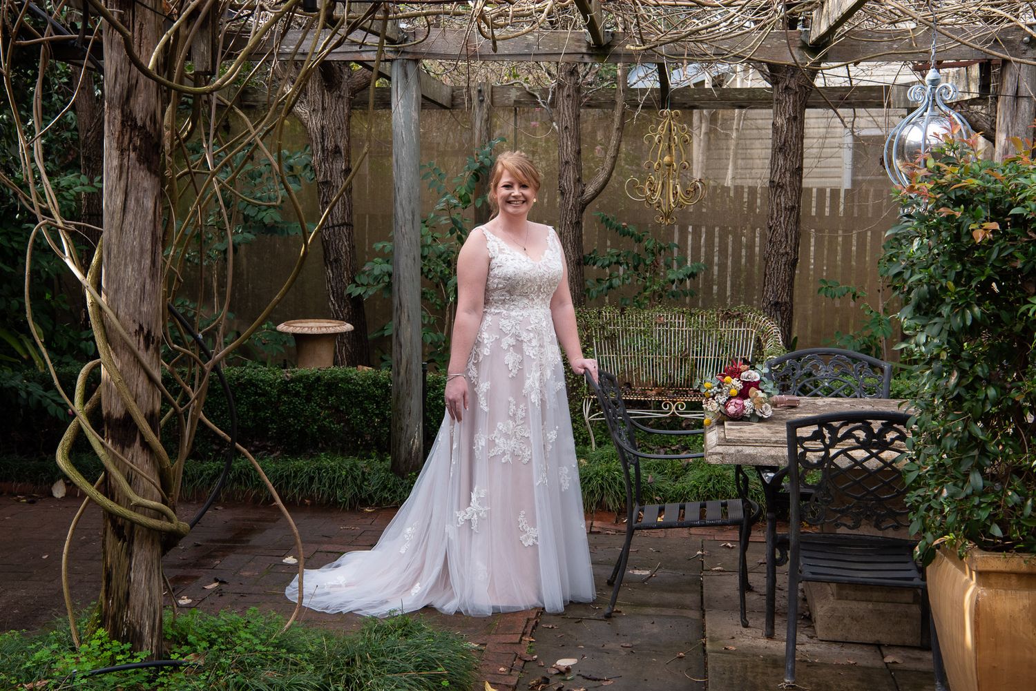 Bride in a floral lace wedding dress walks through a lovely garden setting on her special day.
