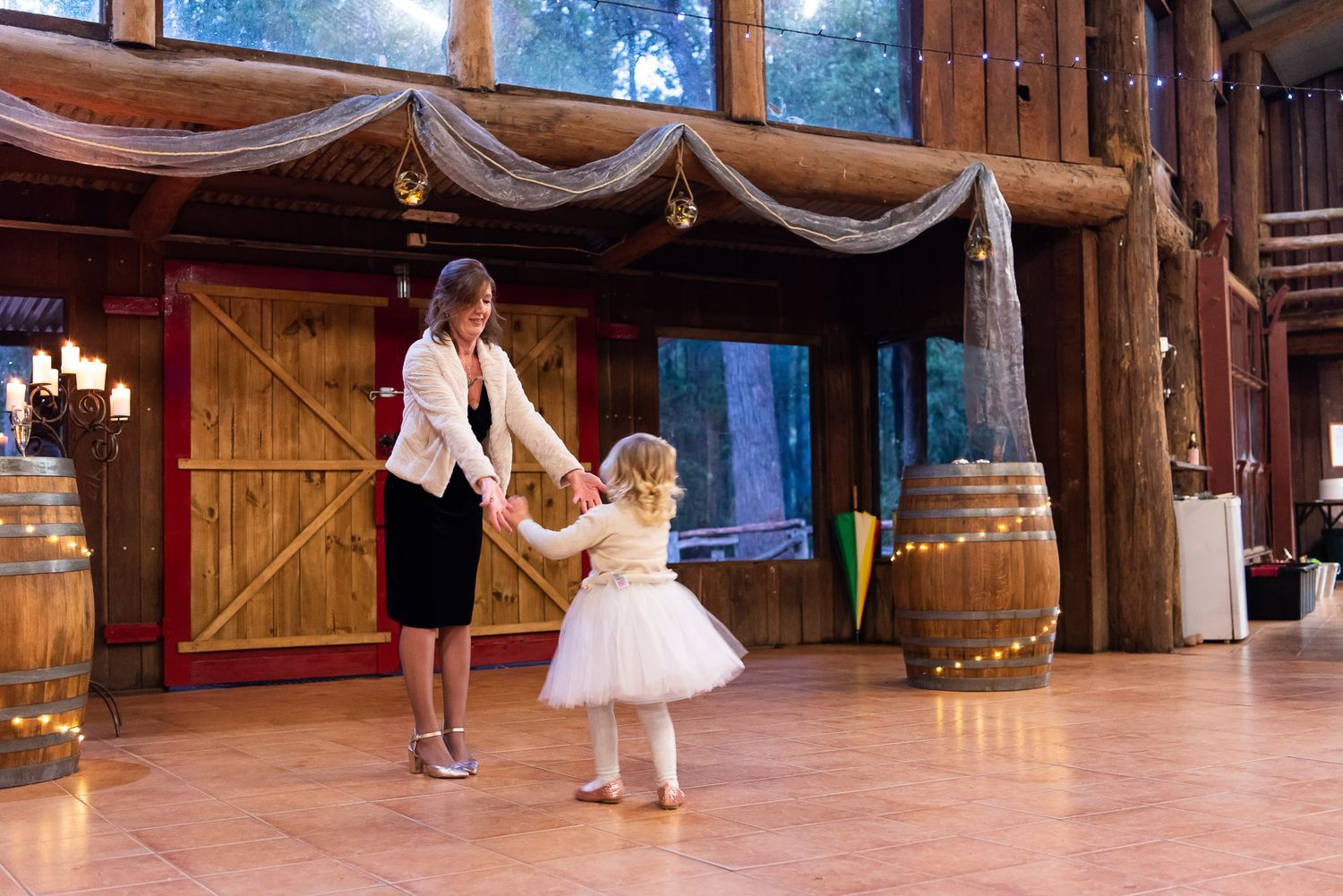Dancers perform in an elegant wood-paneled ballroom decorated with string lights and flowing white fabric.