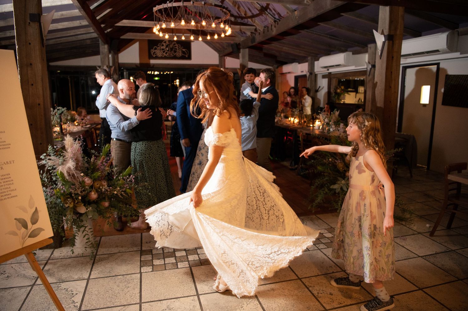 A bride twirling her dress on a dance floor while others celebrate in the background.