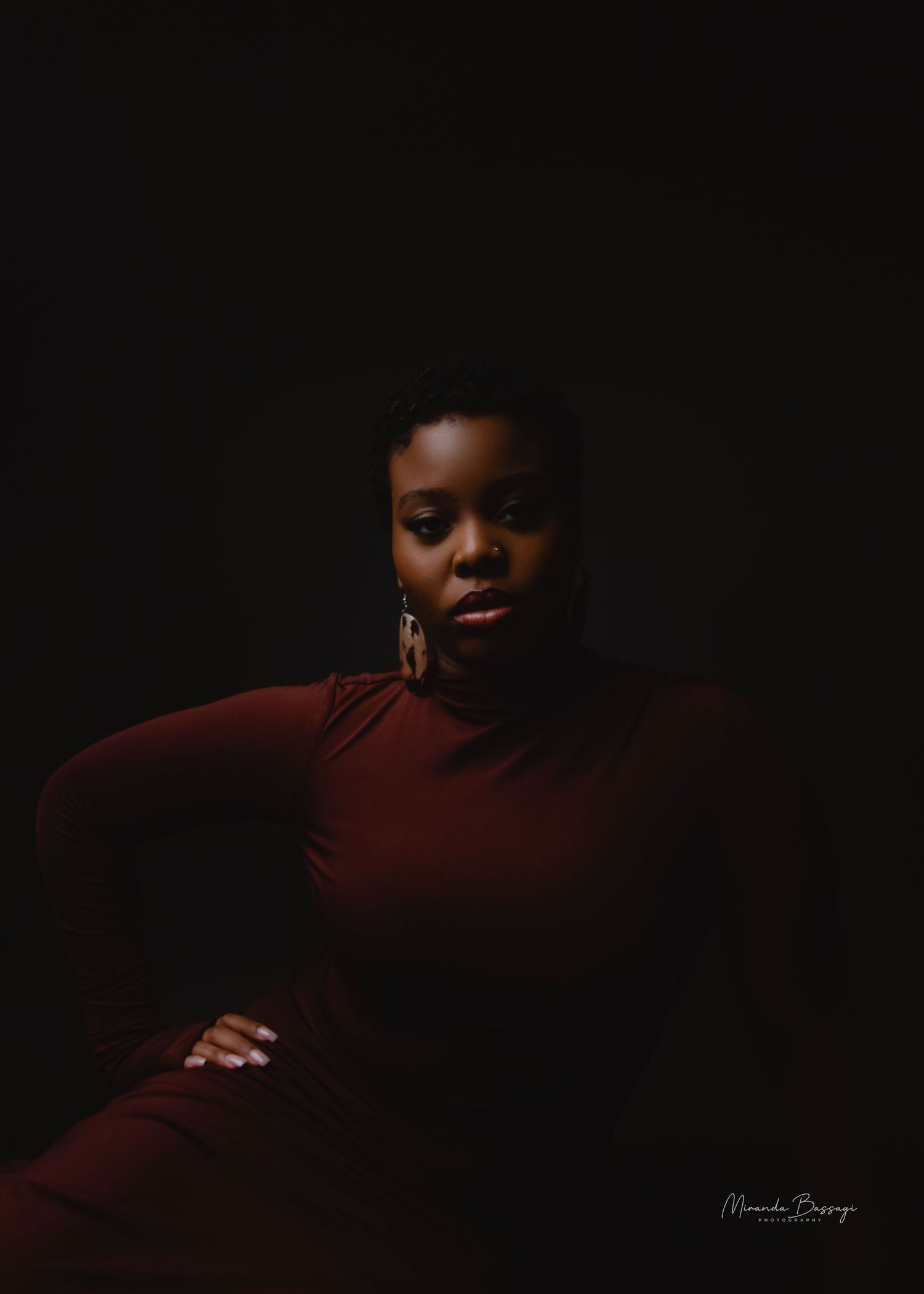 Low-key photography series featuring burgundy outfit in dark studio setting.