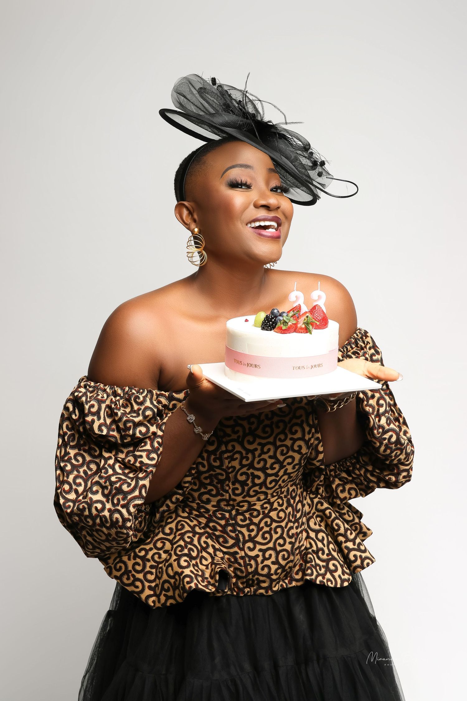 Glamorous portrait series in leopard print off-shoulder dress with black tulle and fancy hat.
