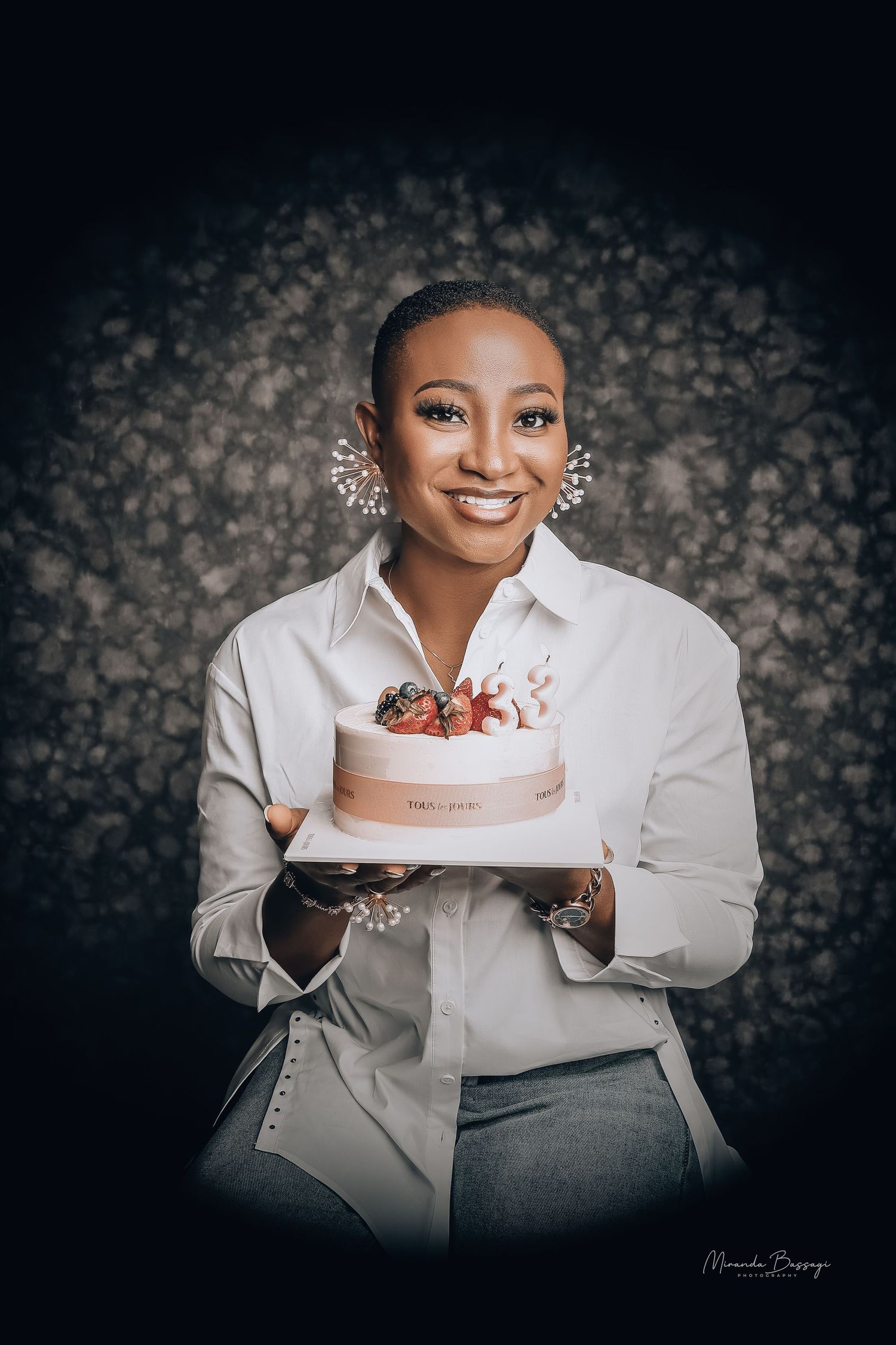Elegant portrait with white cake against dark floral backdrop.
