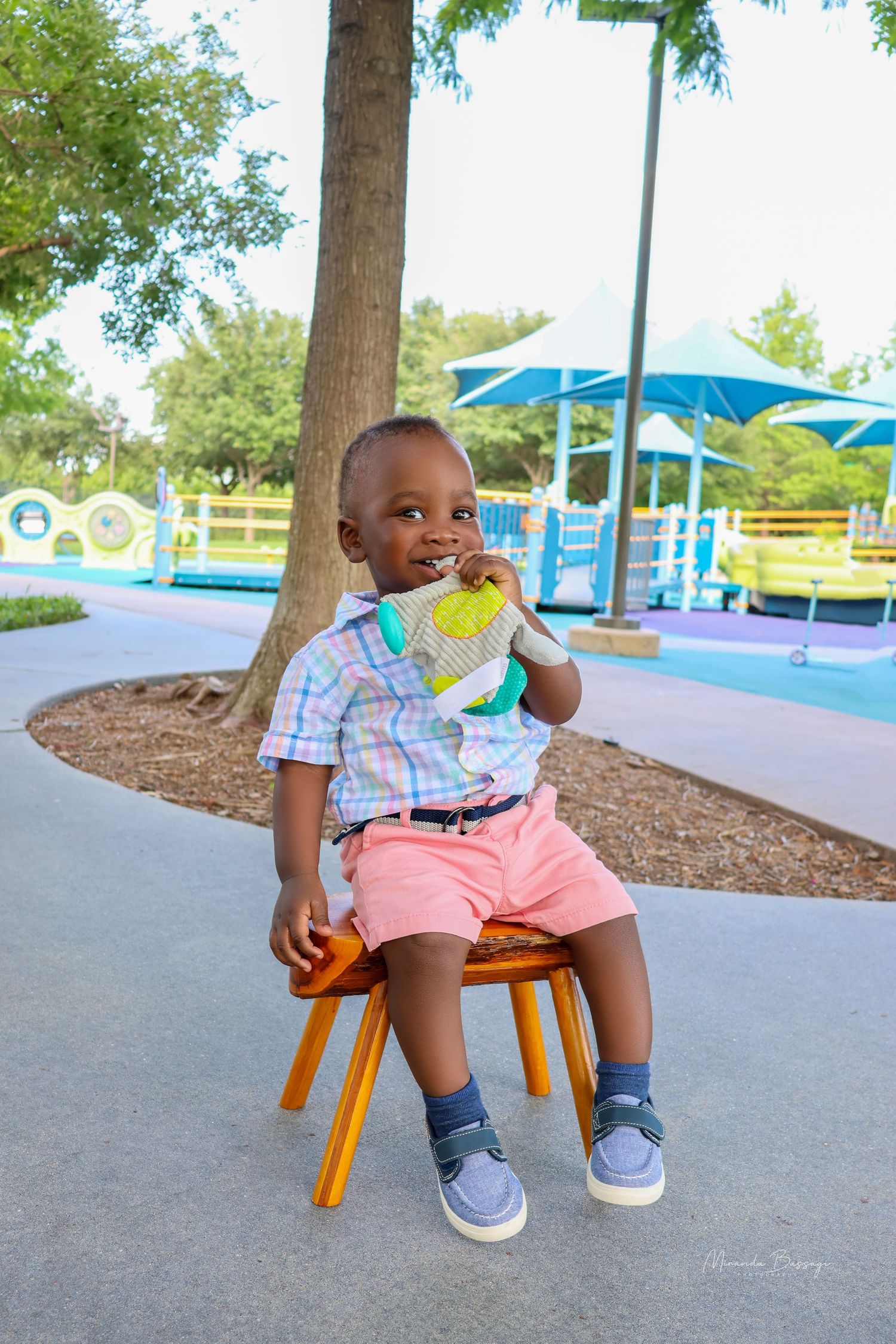 Playful outdoor portraits on wooden bench at playground with blue umbrellas in background.