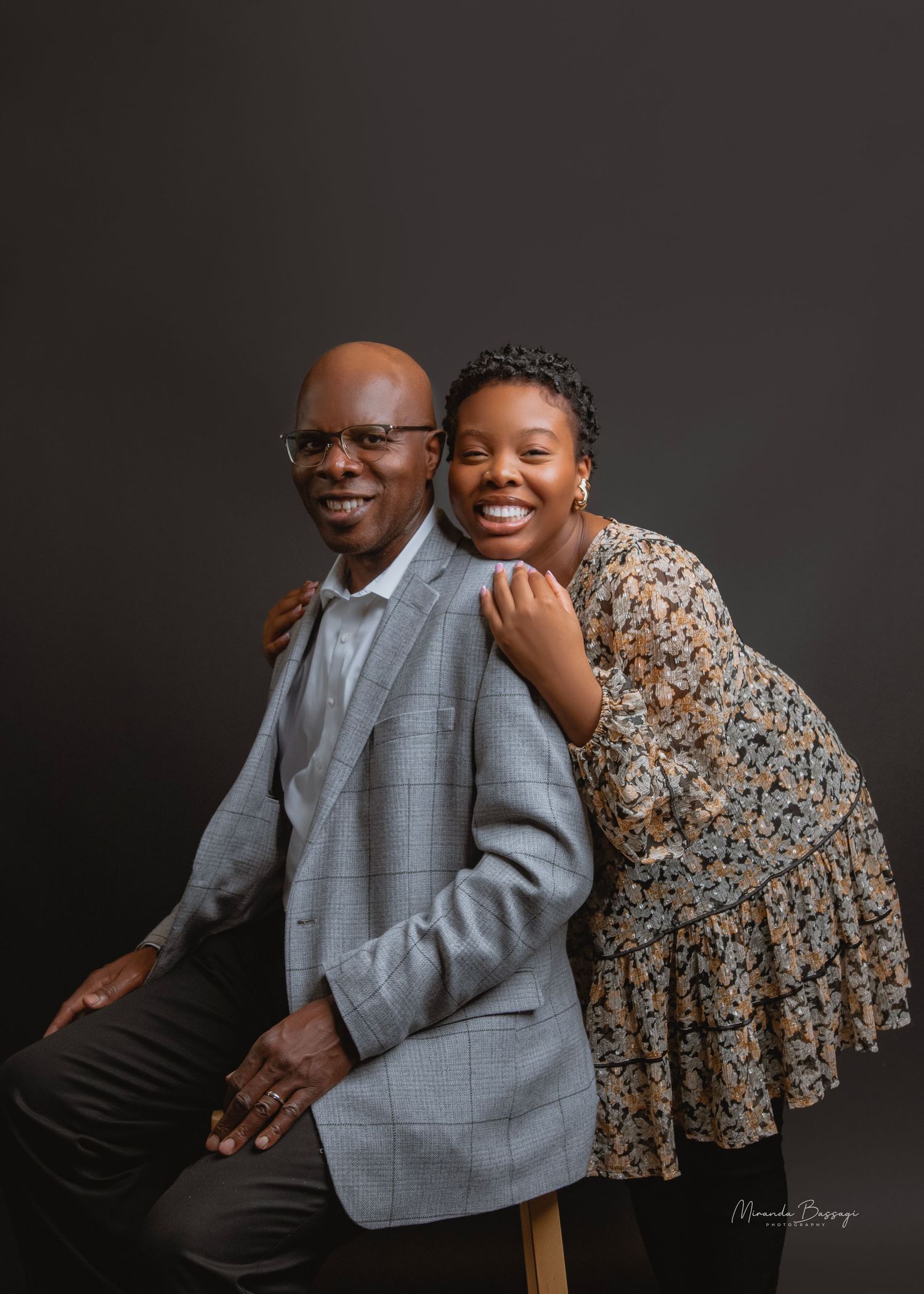 Heartwarming studio portrait of pair in grey blazer and floral dress.