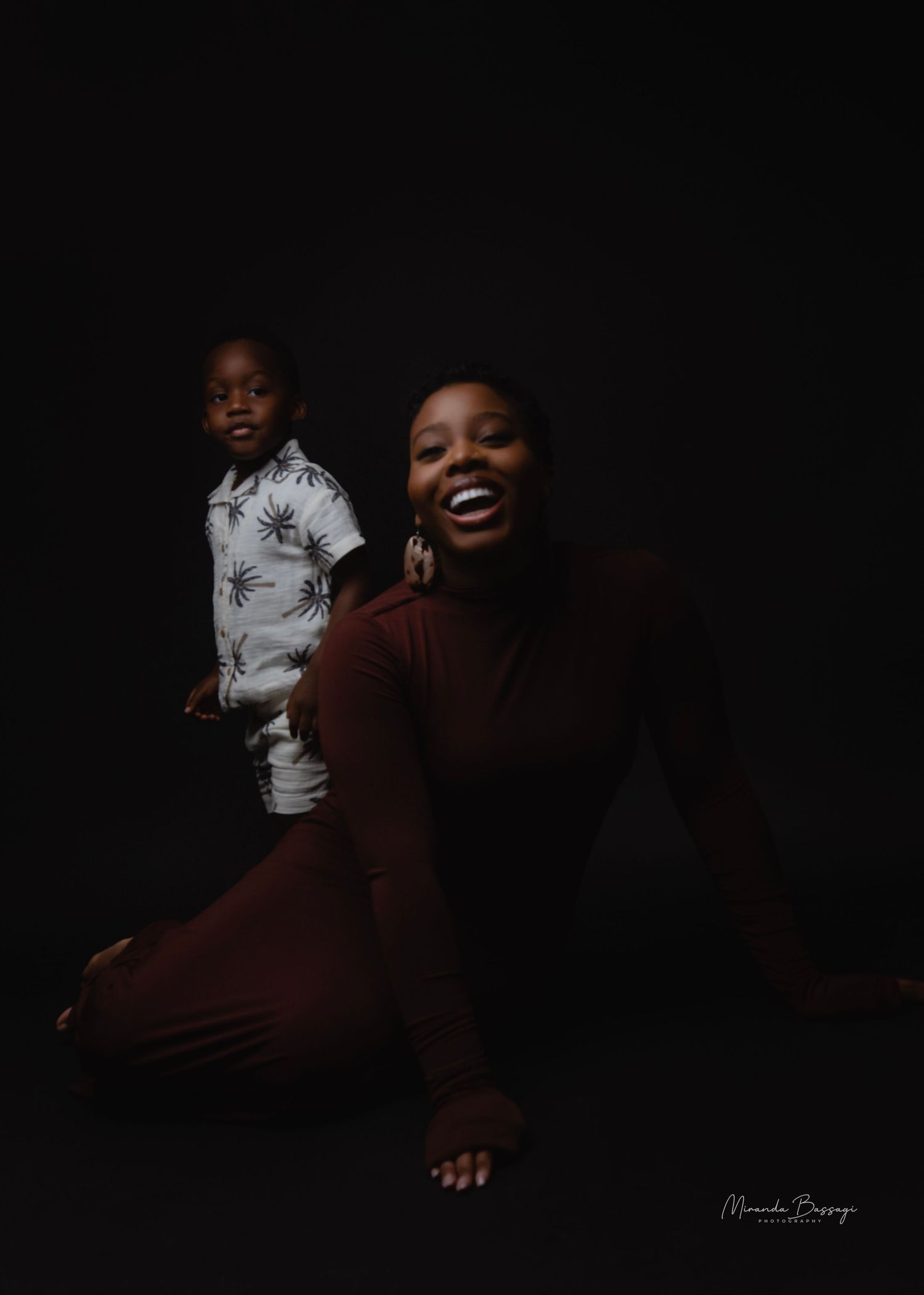 Artistic low-key portraits in burgundy outfit against dark background.