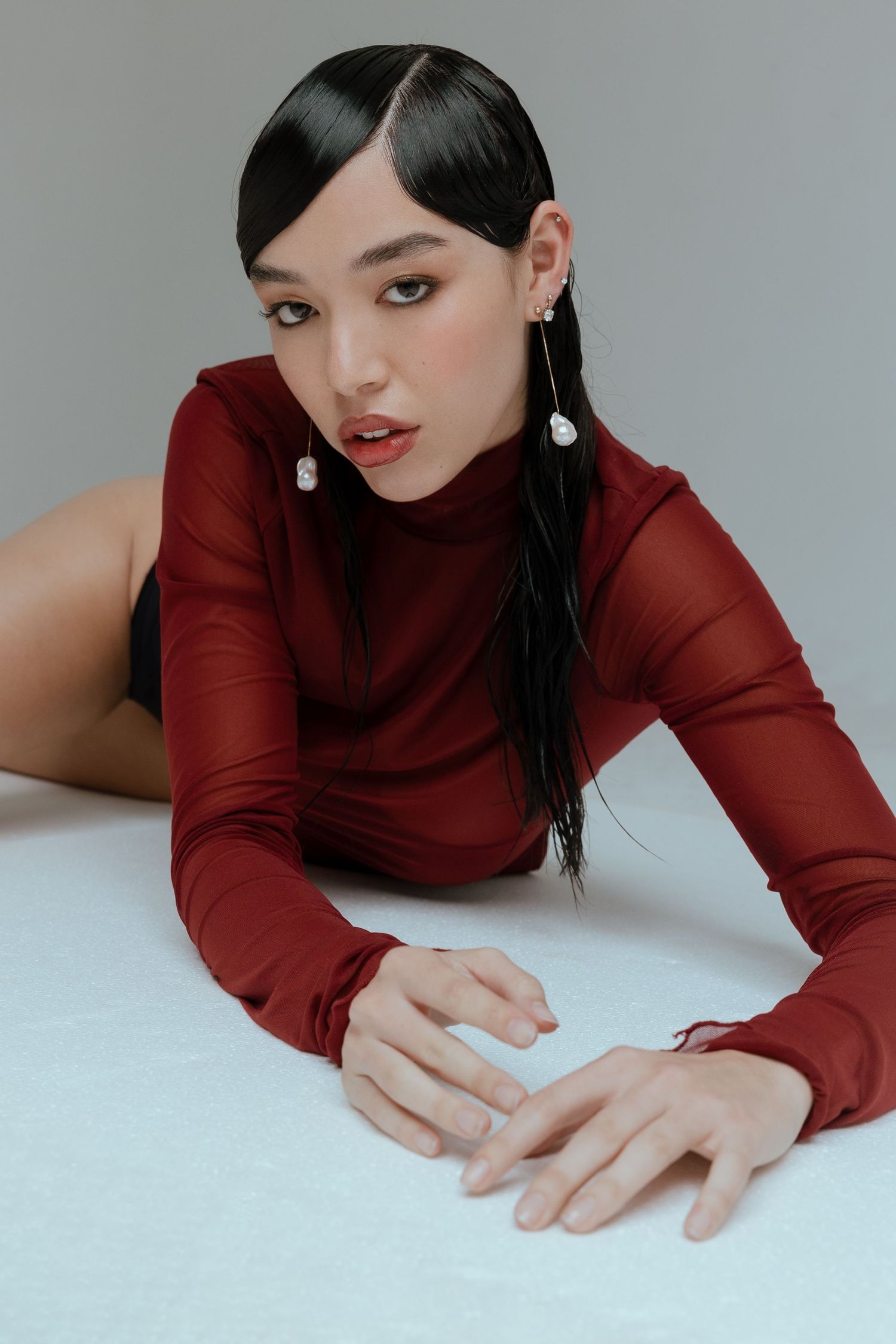 Fashion portraits in burgundy turtleneck against minimalist gray background.