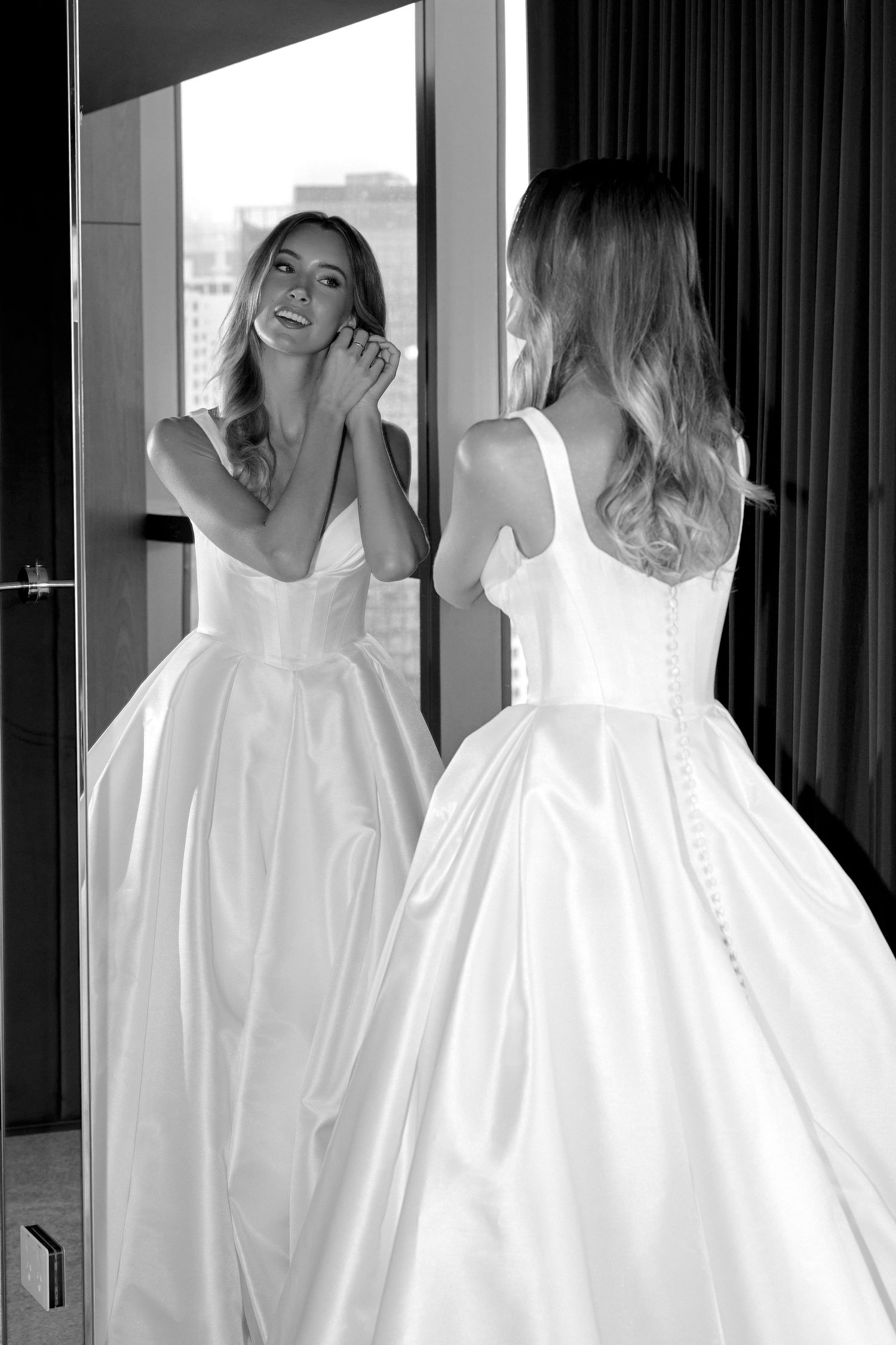 Candid bridal moments in flowing white wedding dress against window light.