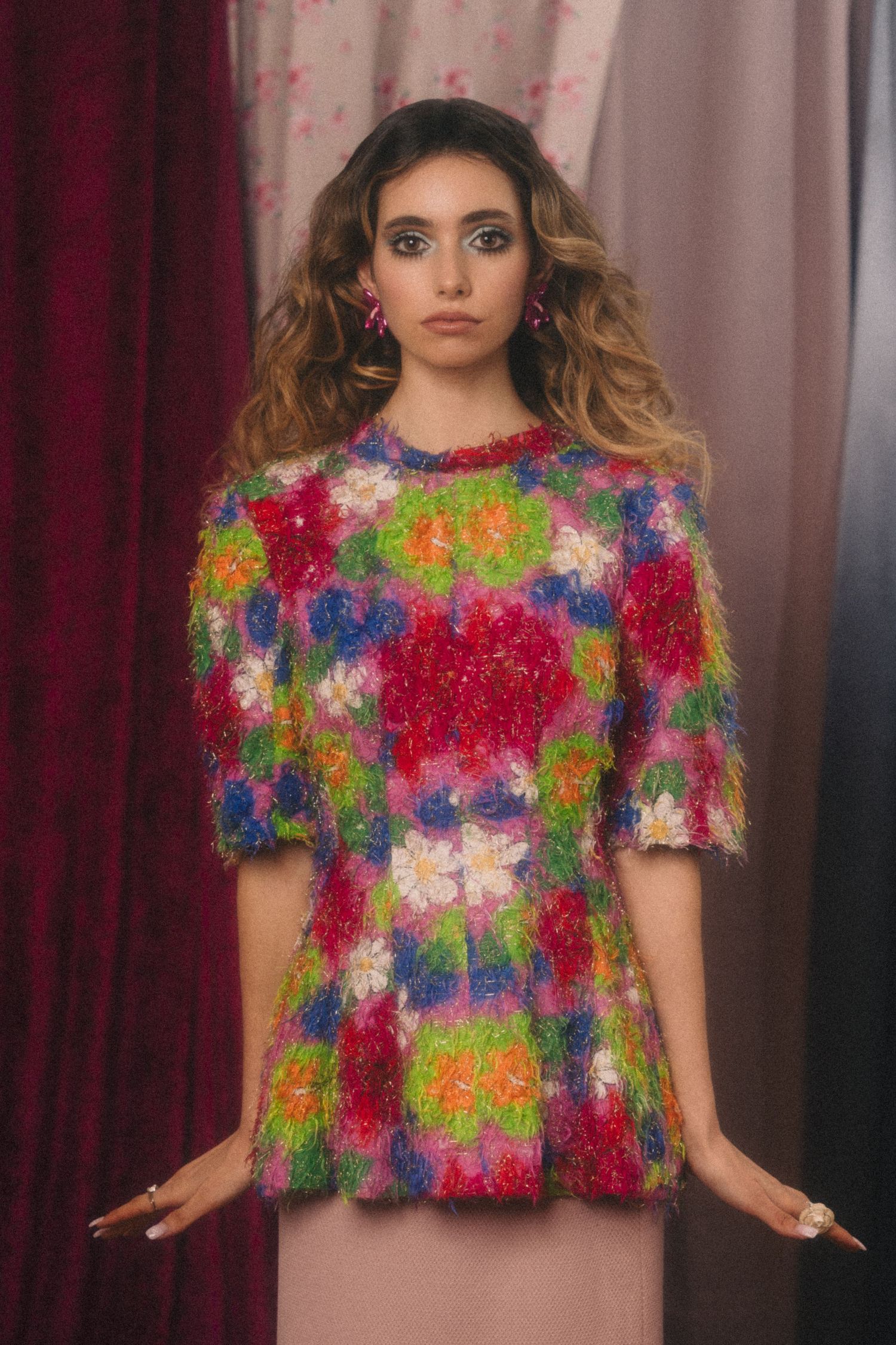 A colorful floral textured crop top made of vibrant multicolored tinsel material against a dark backdrop.