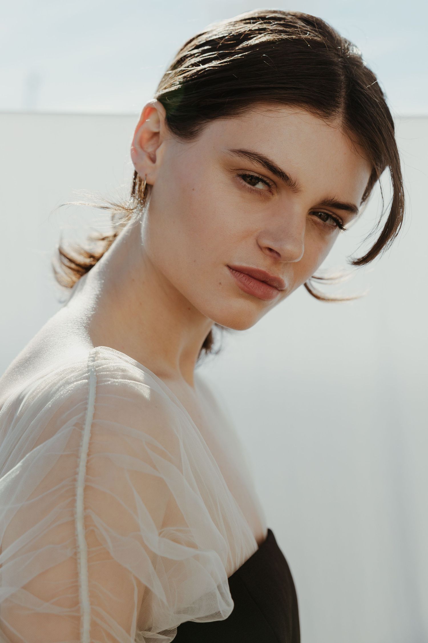 Fashion portrait series against light background showing delicate sheer fabric and contrasting dark attire.
