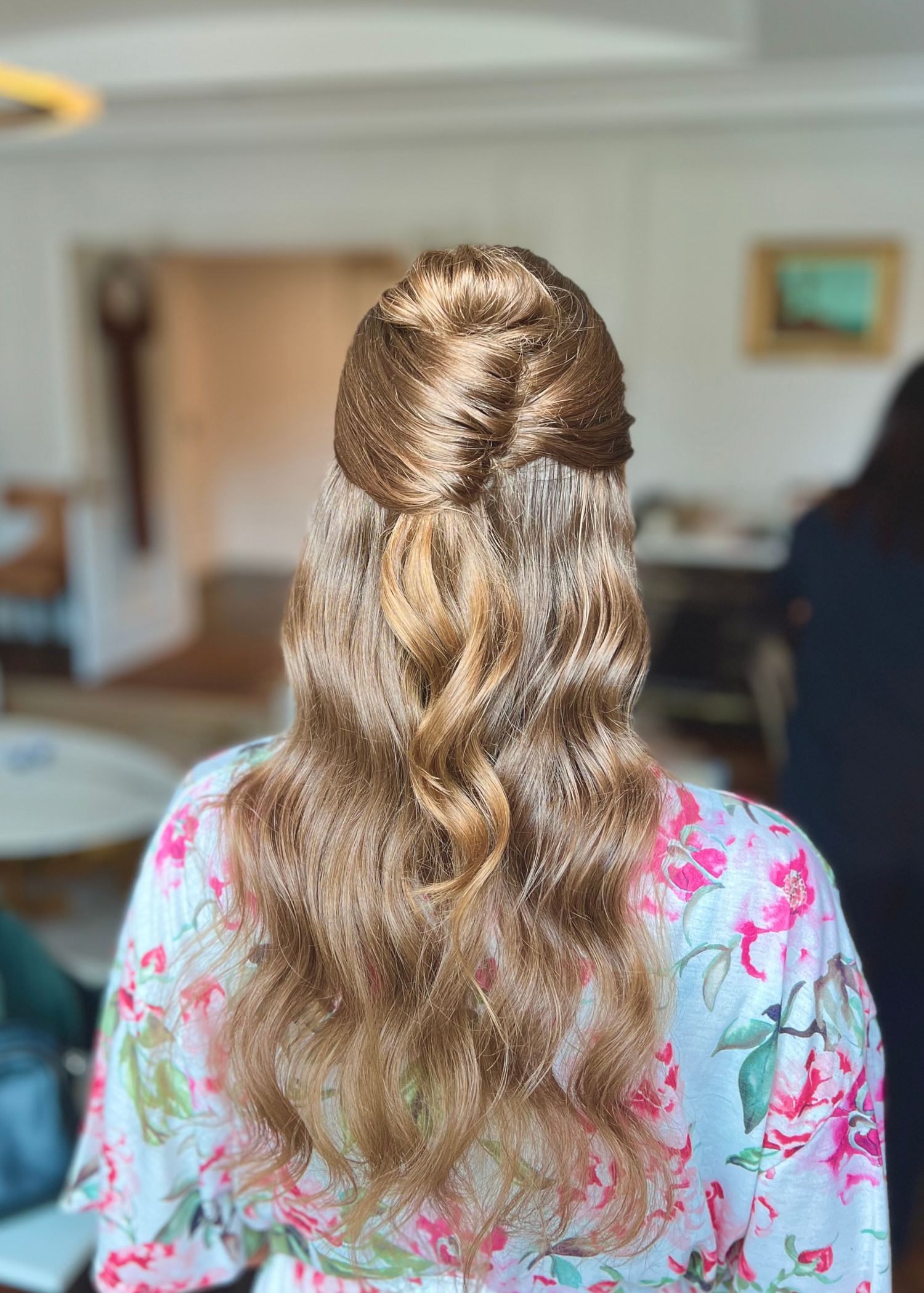 Half-up wedding hairstyle with loose curls and braided details in a floral print robe.