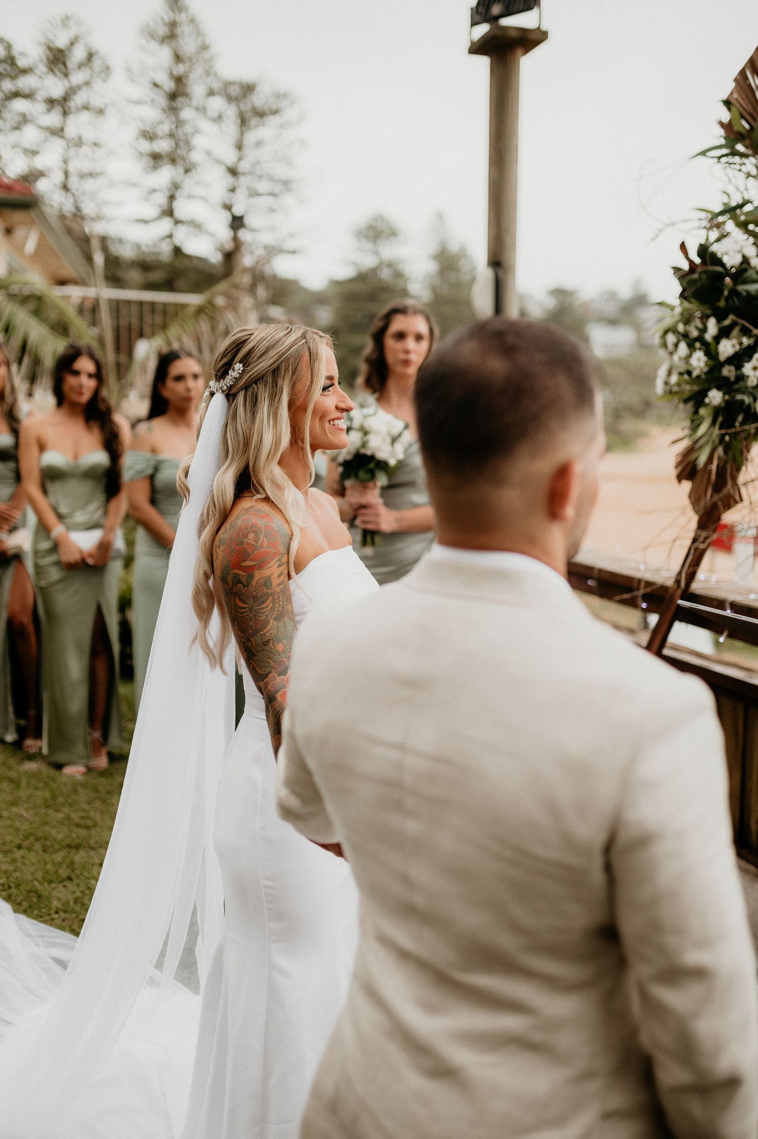 Outdoor wedding ceremony with flowing white dress and sage green bridesmaids.