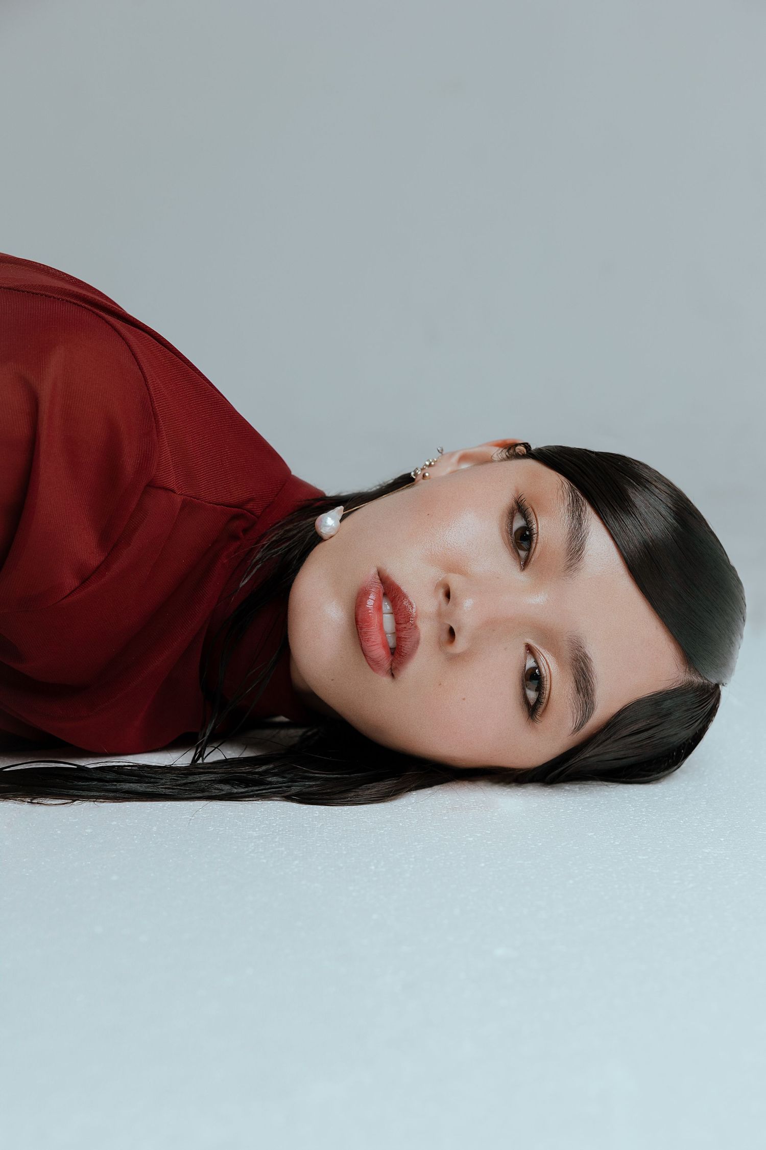 Elegant beauty portraits with sleek hair and red clothing against gray backdrop.