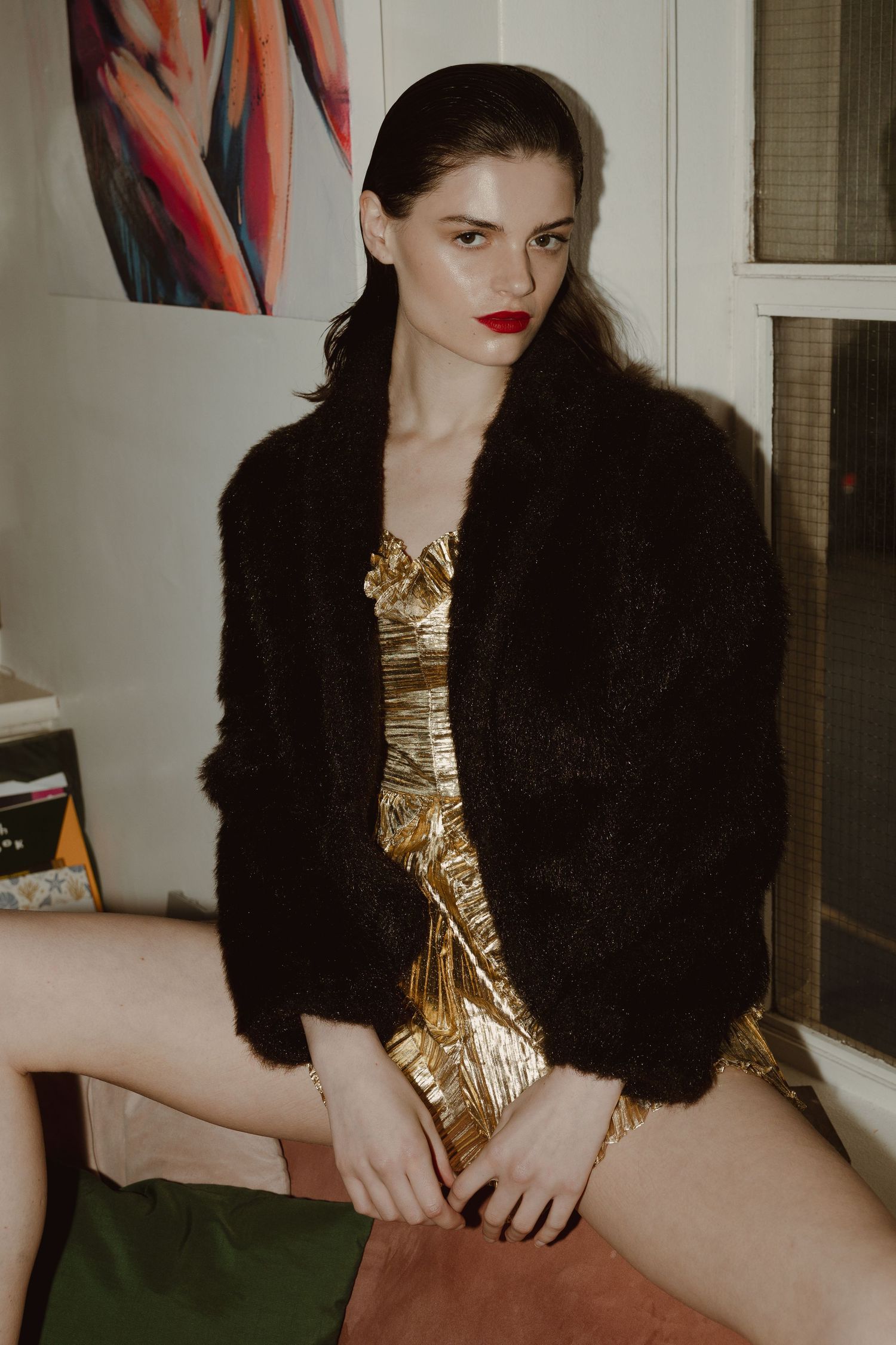 A model poses in a luxurious gold sequin dress paired with a black fur stole in a fashion photoshoot series.