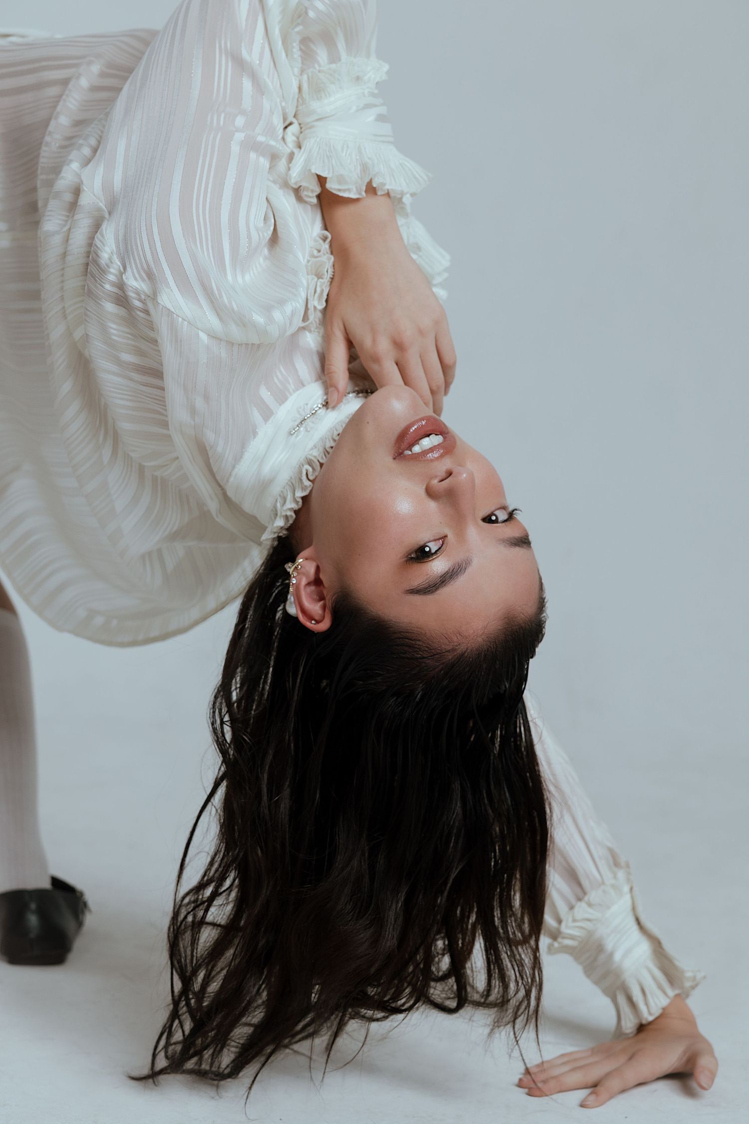 Artistic portrait series of model in white dress captured from dramatic angles against light background.