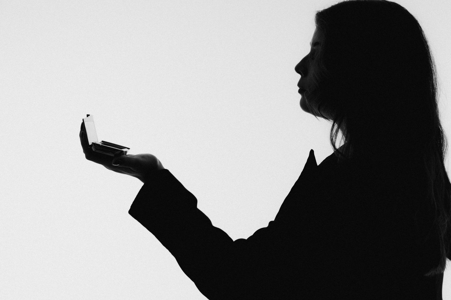Collection of black silhouettes showing makeup application poses.