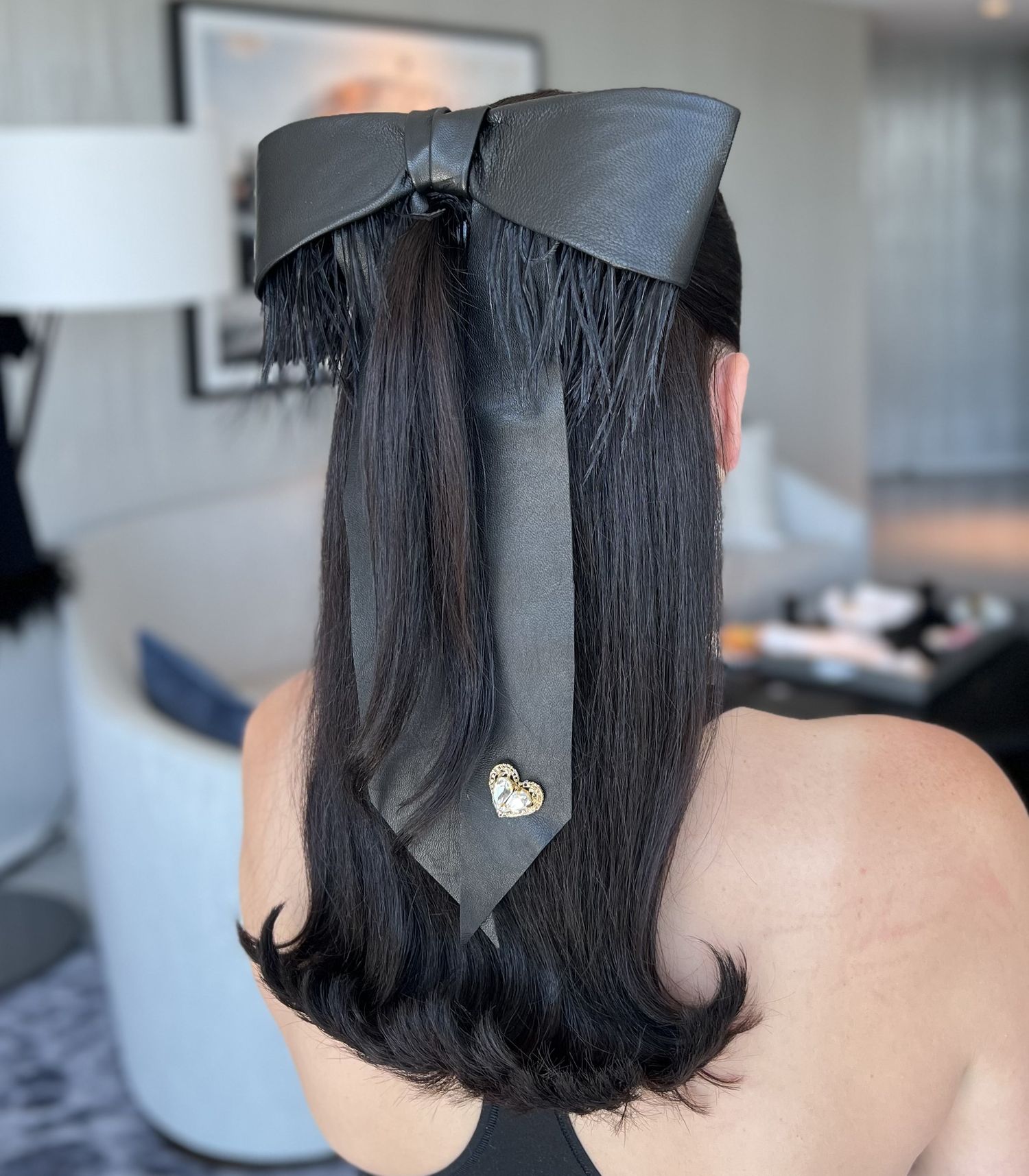 Black satin bow with fringe detail adorned with a small heart charm.