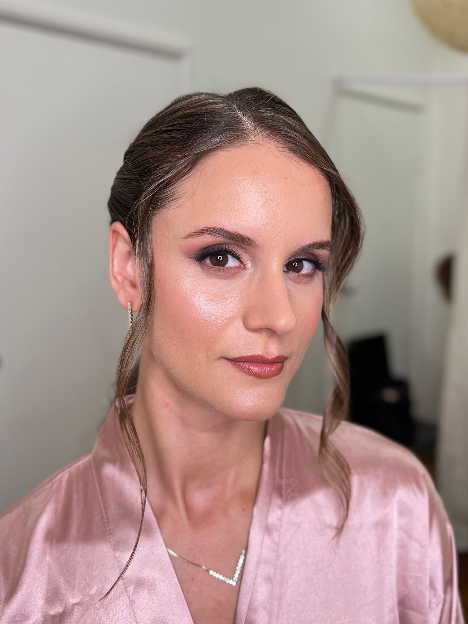 Soft glam makeup look with updo hairstyle and pink satin robe.