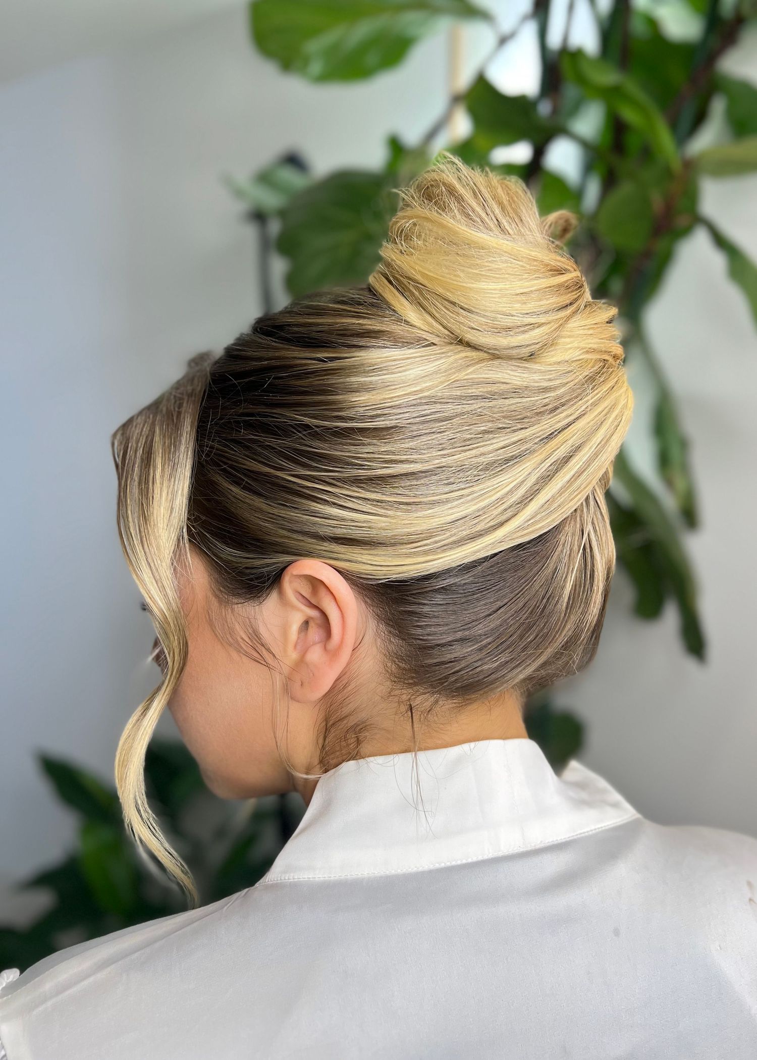 Close-up view of blonde updo hairstyle from behind with white collar.