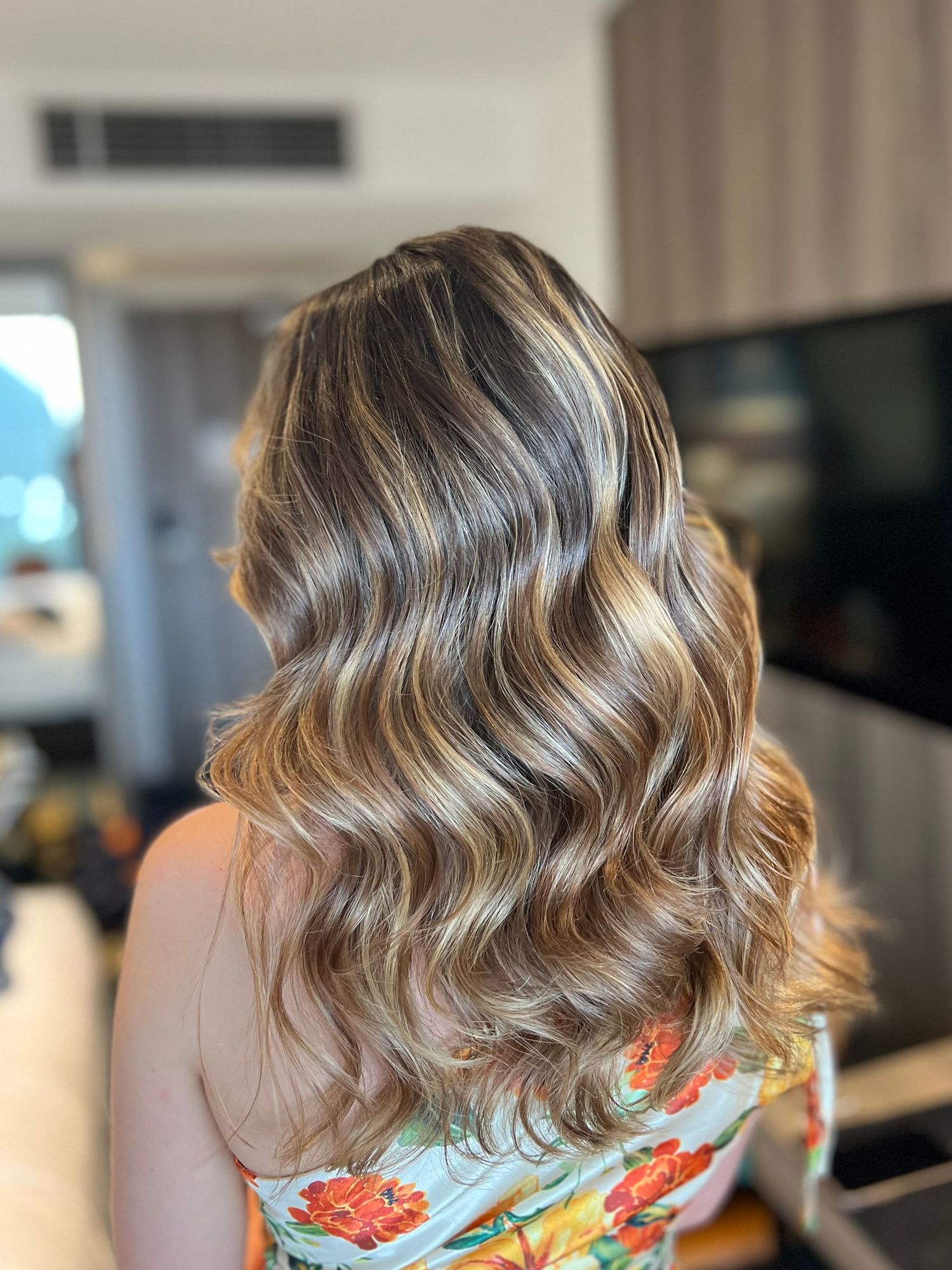Glamorous wavy hairstyle with caramel and blonde highlights.