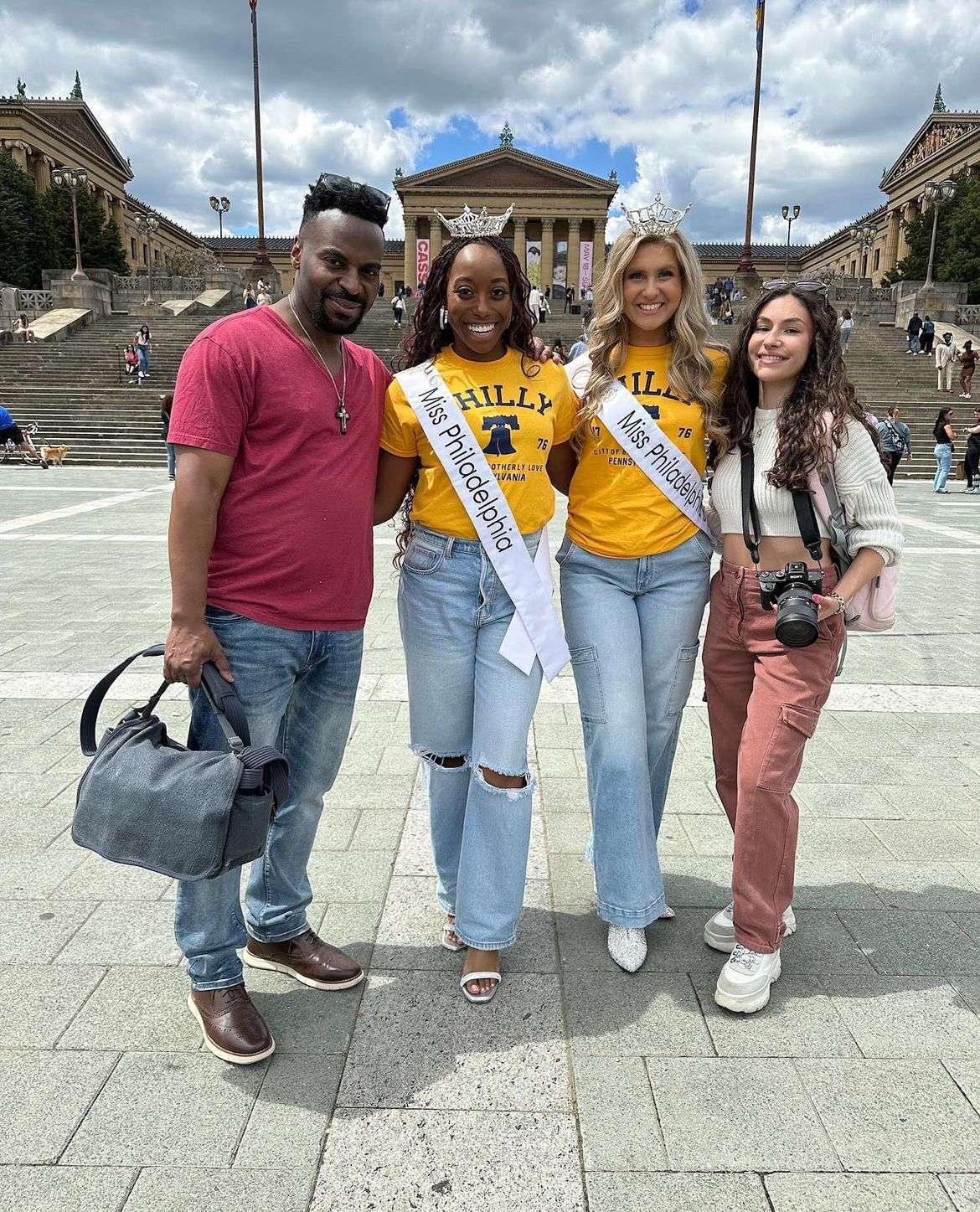 Two Miss Philadelphia pageant winners in yellow shirts posing with fans on the Philadelphia Museum of Art steps.
