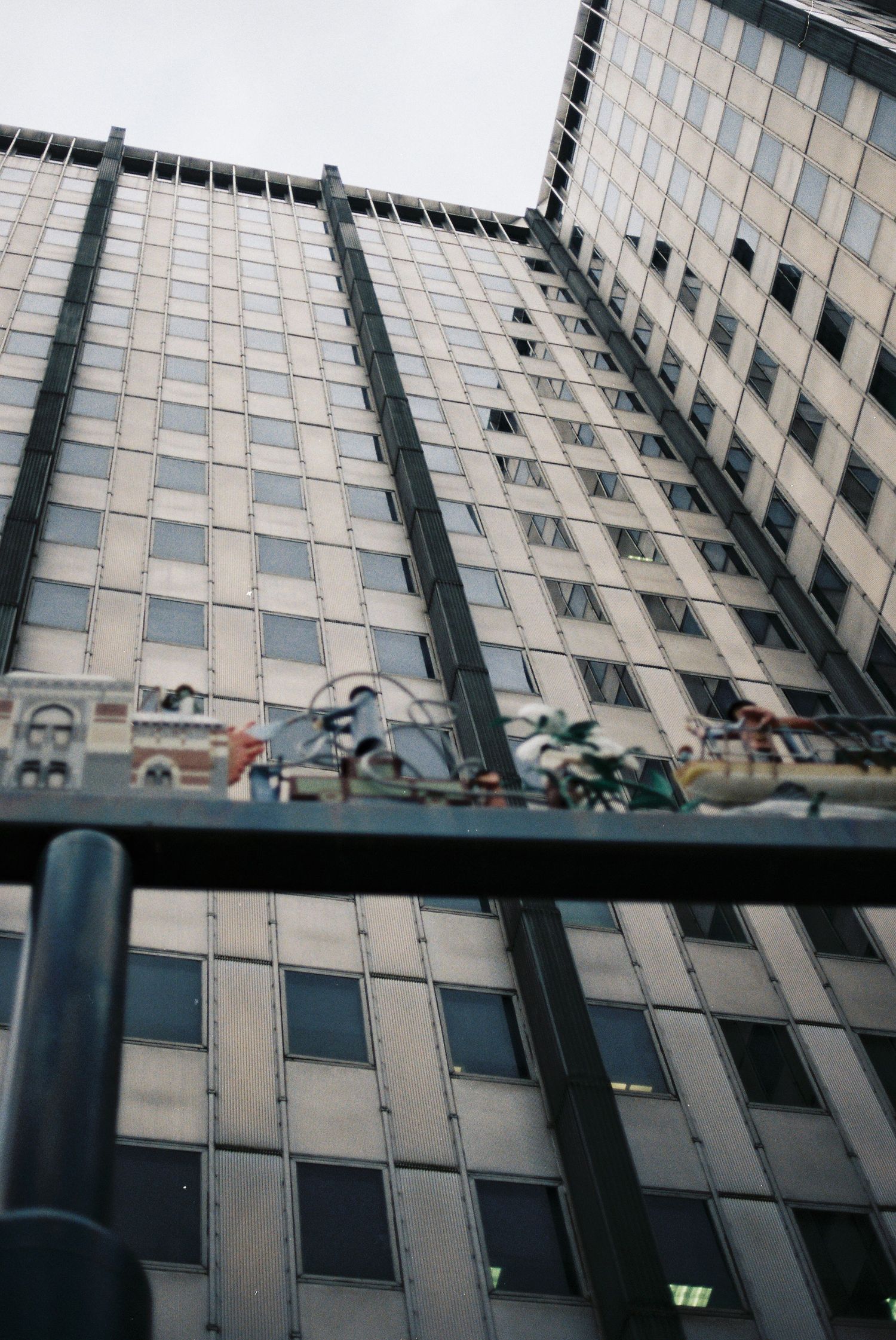 Low angle view looking up at a tall glass and steel skyscraper facade in an urban city.
