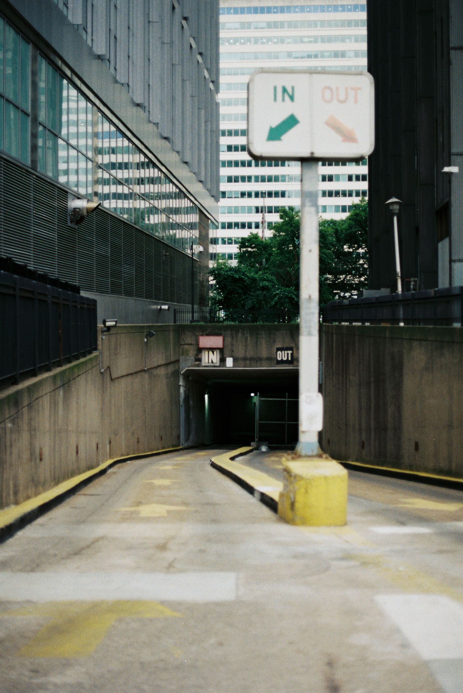 Urban parking garage entrance with IN and OUT directional signs surrounded by city buildings.