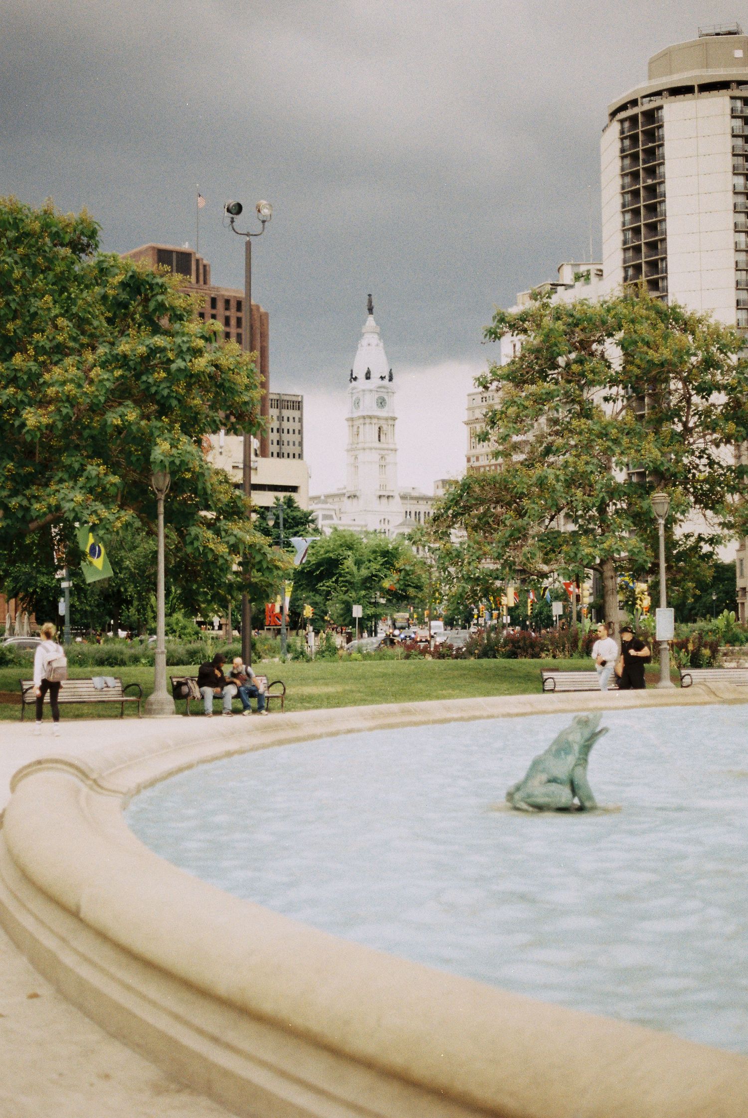 A fountain in a city park with Philadelphia City Hall visible in the background.