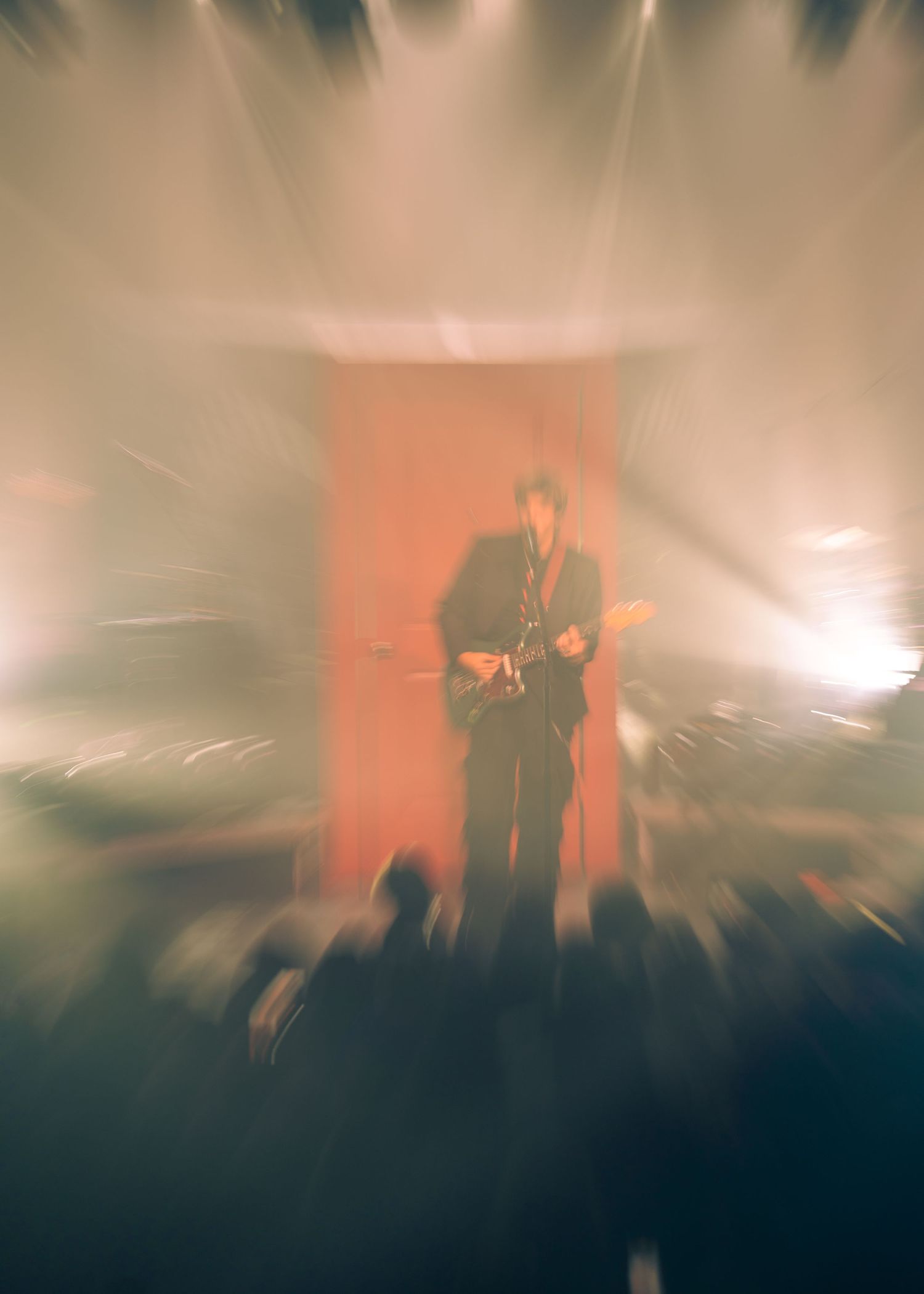 Singer performing in warm orange stage light and haze during a Philadelphia concert
