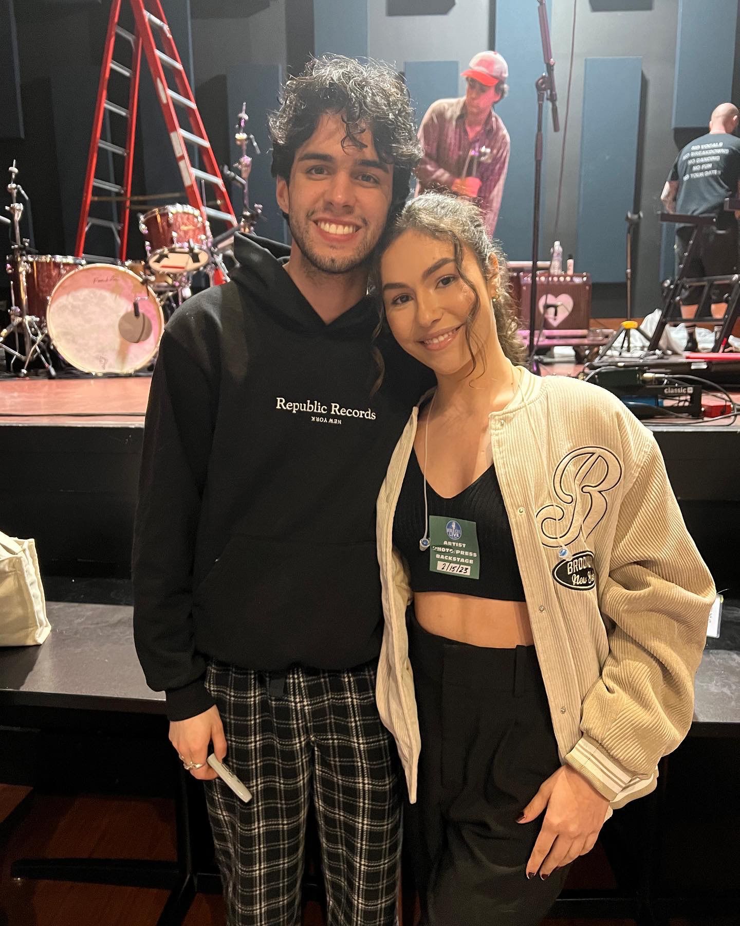 Stephen Sanchez and Arianna posing together backstage at a music venue with Republic Records hoodie visible.