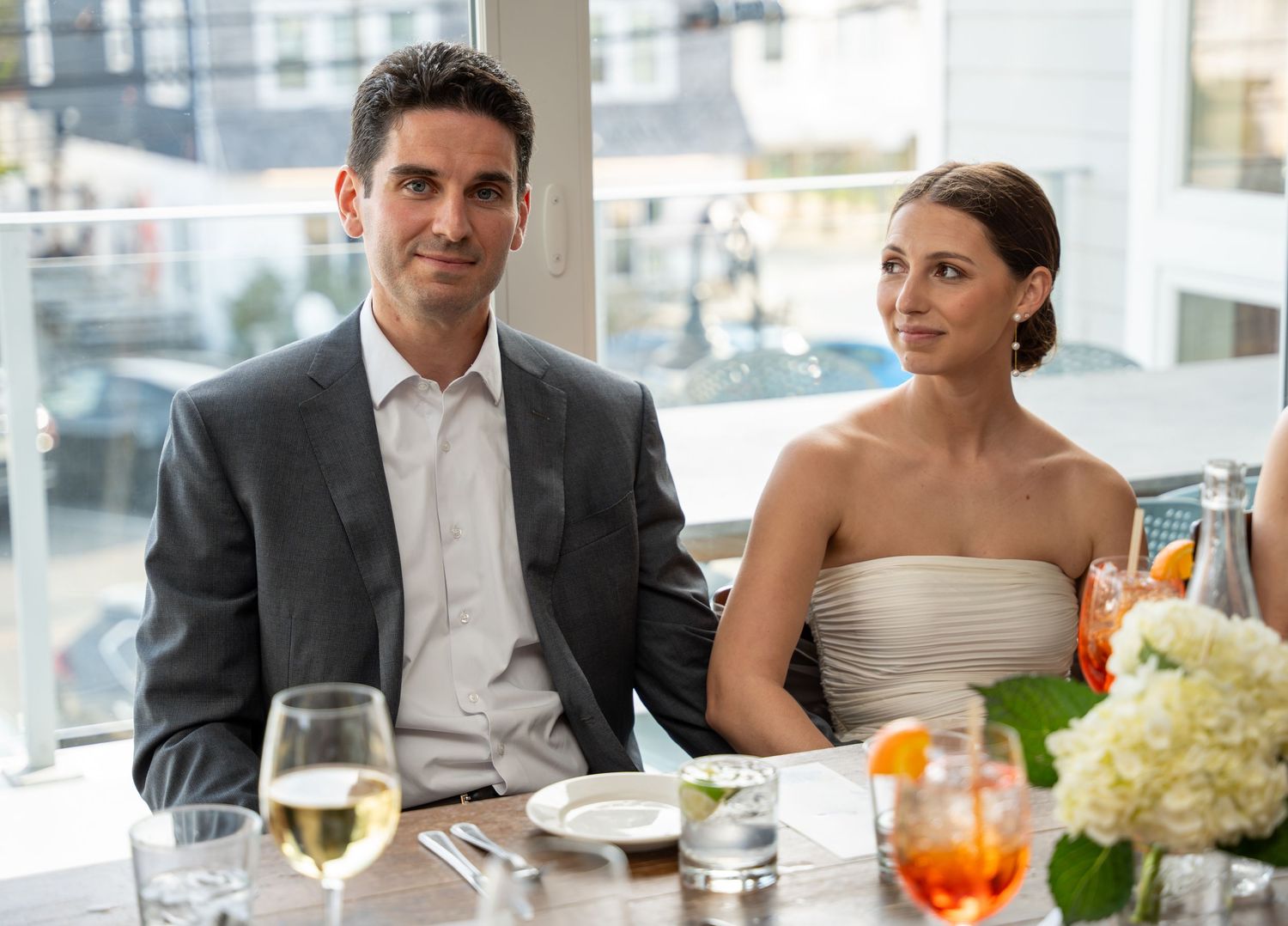 Smiling bride and groom seated together at elegant wedding reception dining table.
