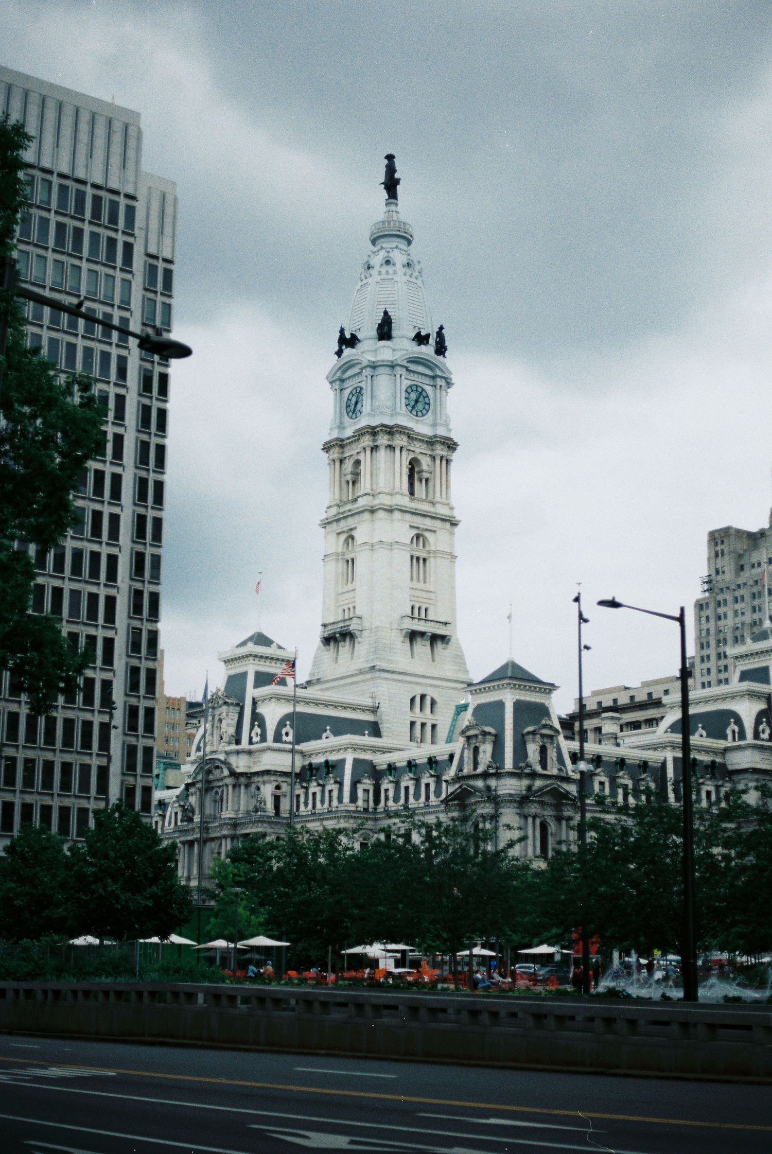 Philadelphia City Hall tower with ornate white architecture and clock faces against a cloudy sky.