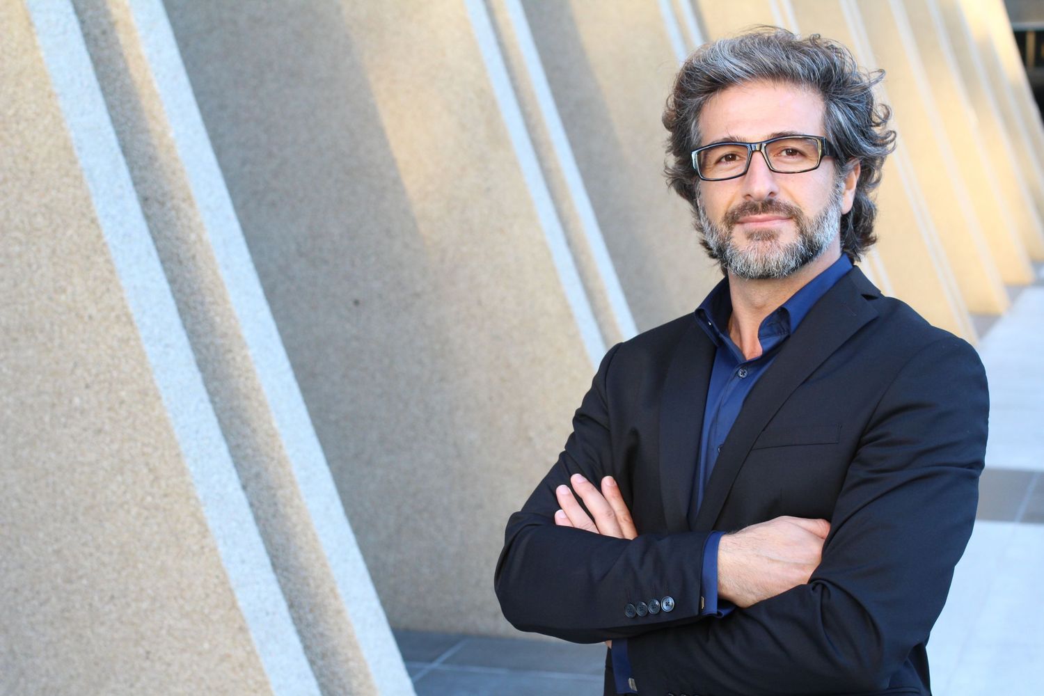 Professional portrait against concrete pillars in warm lighting.