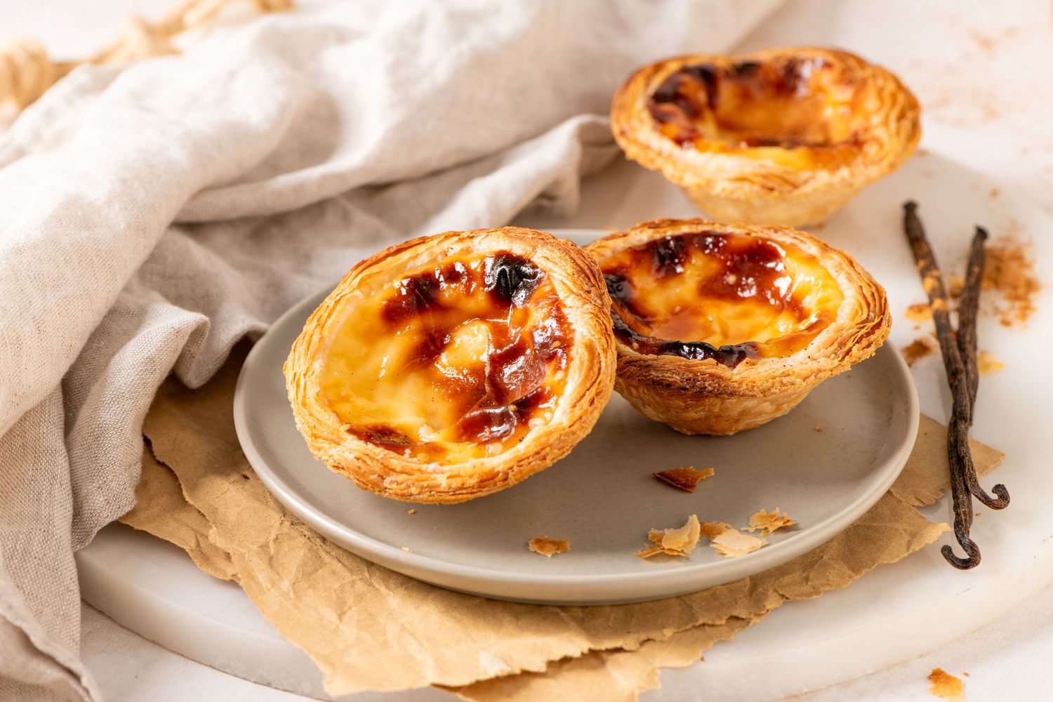 Freshly baked egg tarts with golden brown tops arranged on white plates.