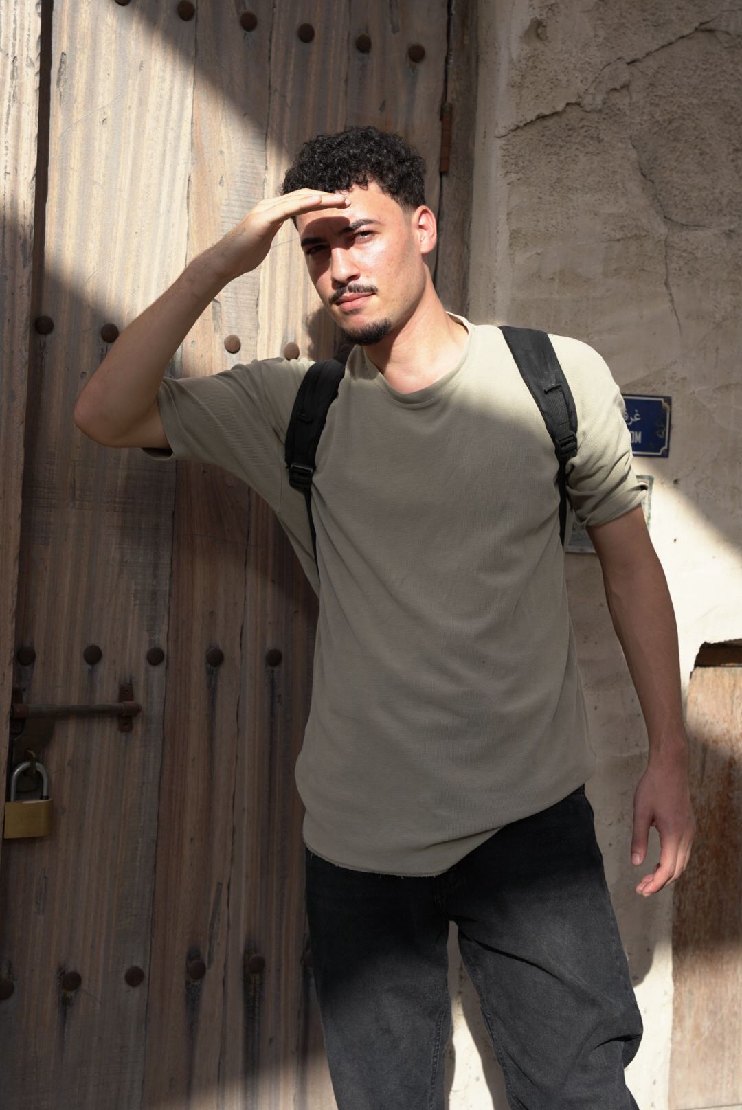Dynamic poses against a textured wall showing movement in casual attire with a backpack.