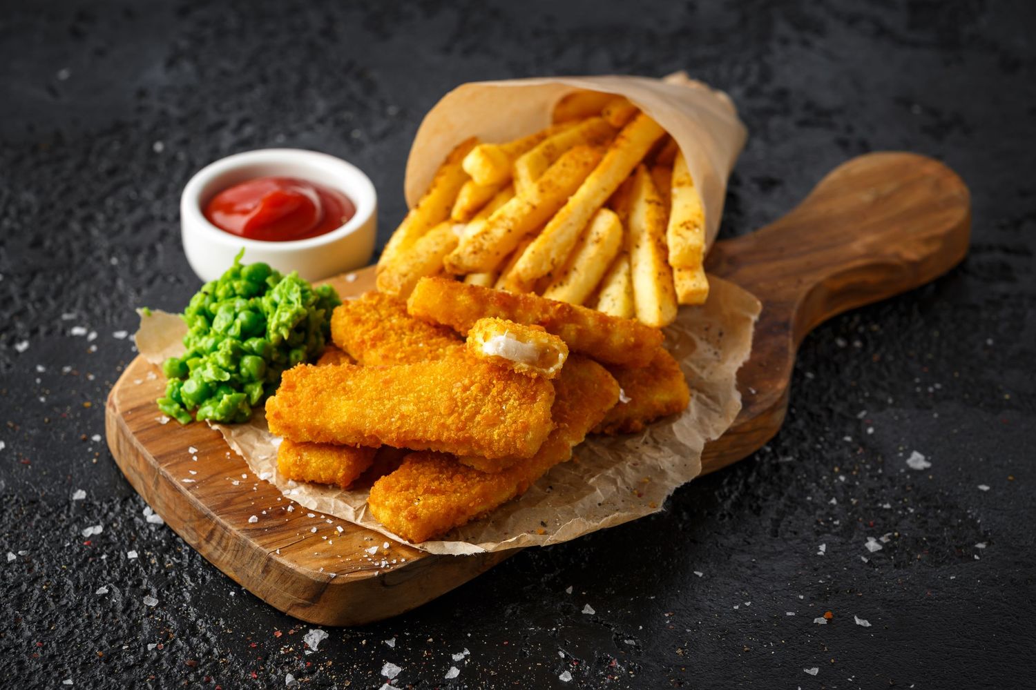 Golden crispy fish and chips served on wooden boards with ketchup and garnish.