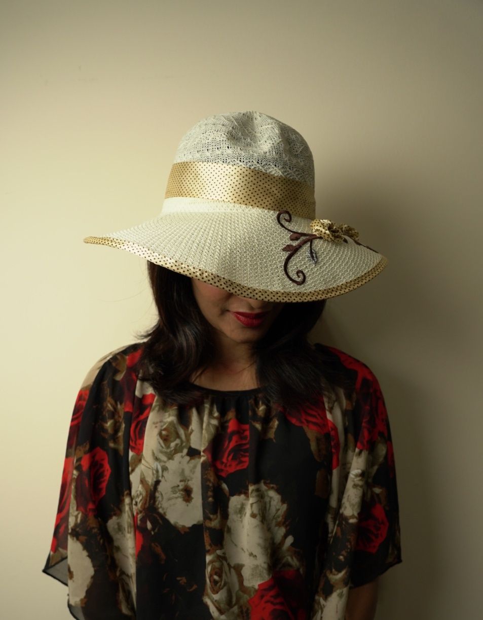 Elegant straw sun hat and floral dress against a neutral background.