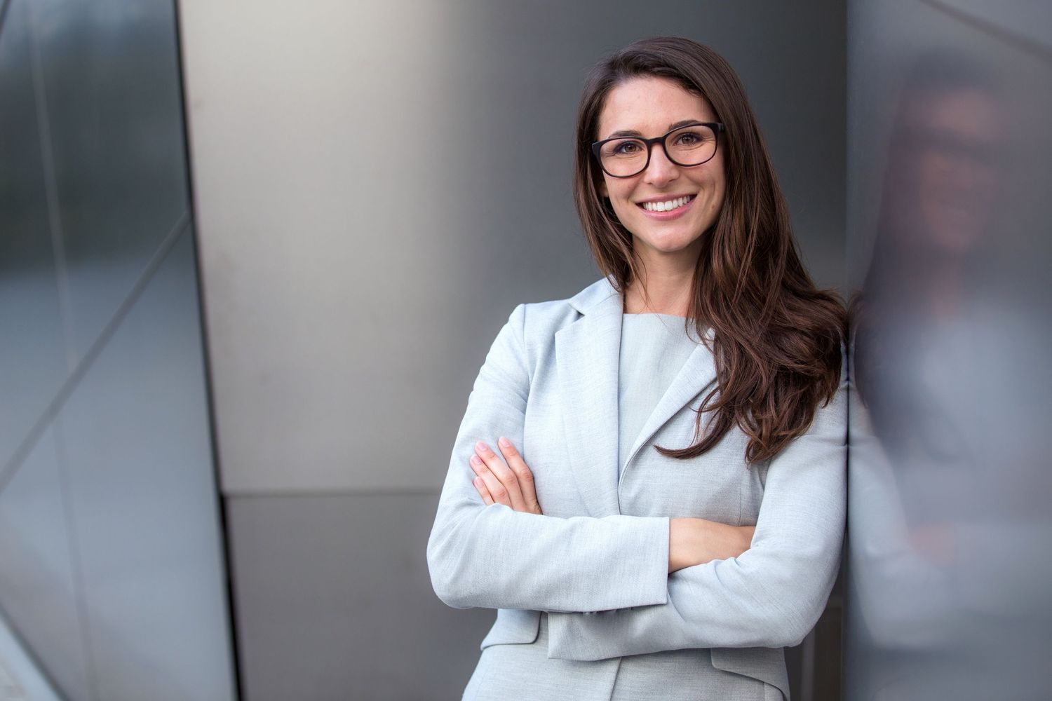Professional woman in business attire posing against grey background.