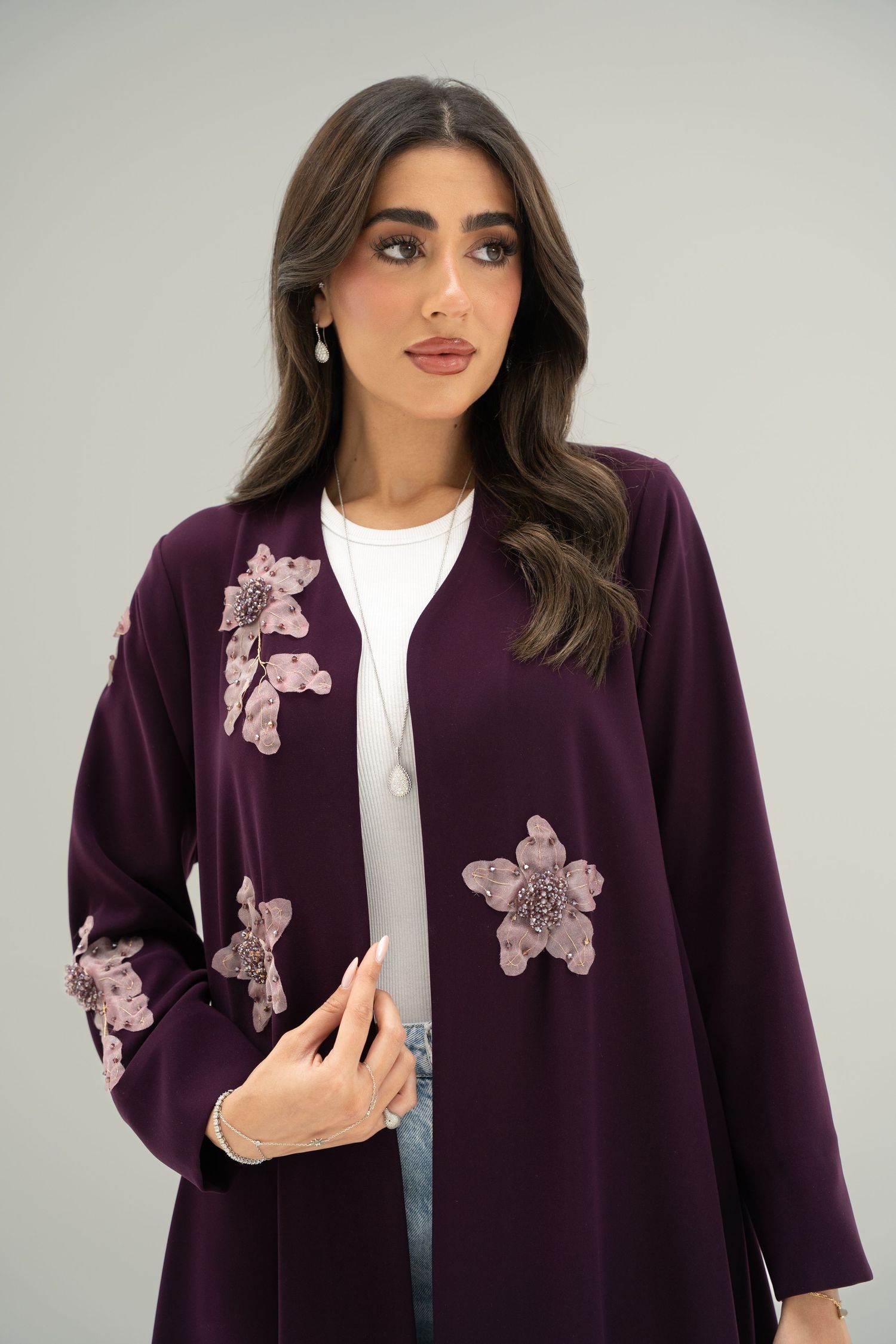 Purple cardigan with pink butterfly appliques styled with white top against light gray background.