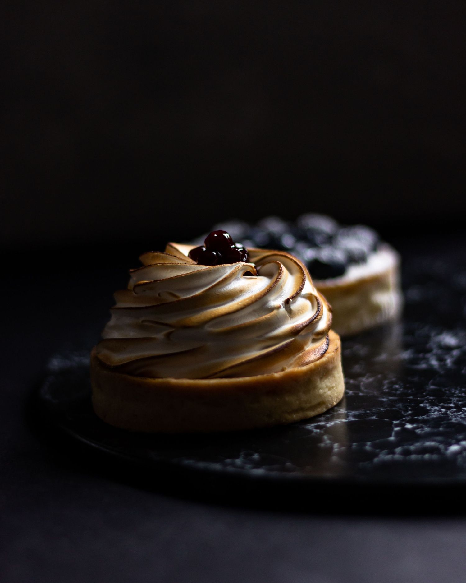 Artistic close-up shots of swirled meringue cookies on dark background.