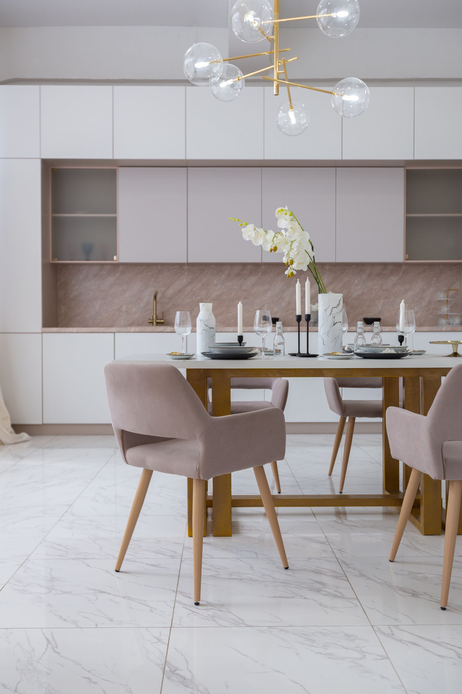 Elegant dining room with glass pendant lights and upholstered chairs on marble flooring.
