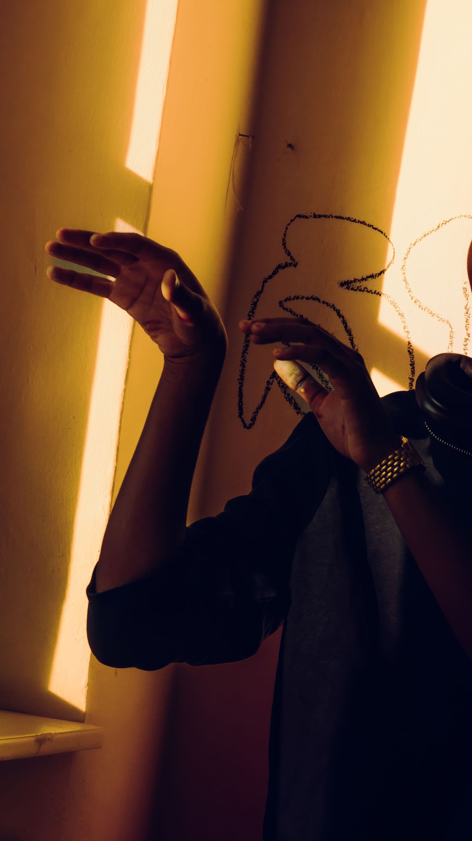 Shadow play with hands against golden sunlit wall.