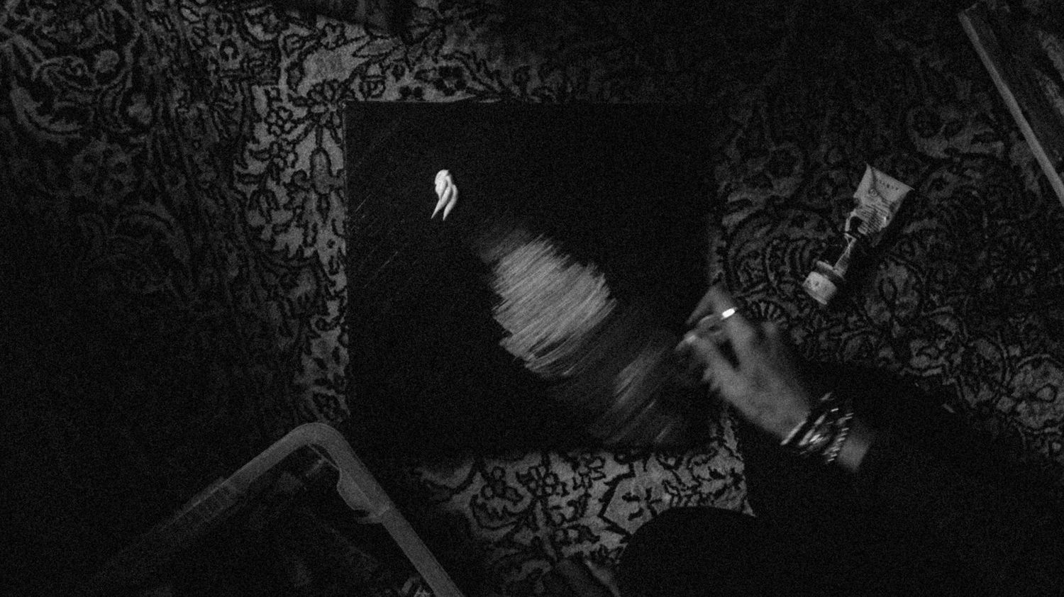 Dark moody photoshoot with ornate wallpaper background creating dramatic shadows.