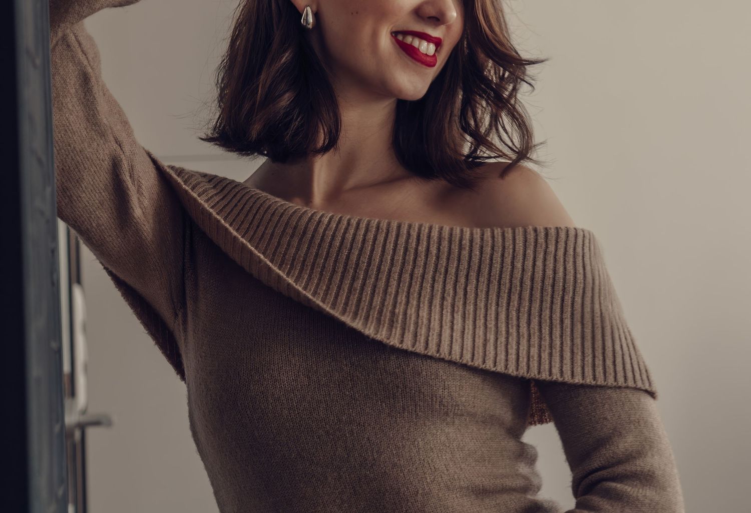 Fashion detail of brown off-shoulder ribbed sweater in natural light.