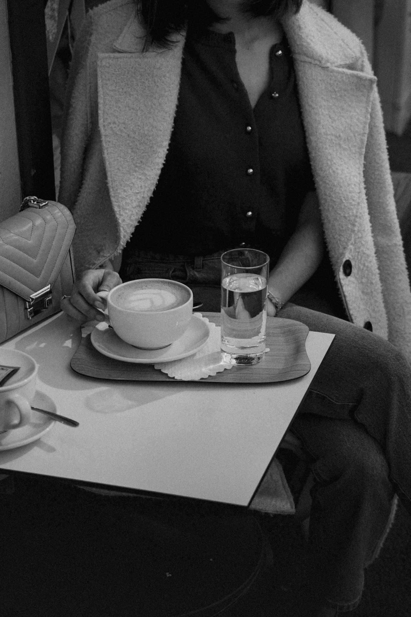 Black and white cafe scene showing coffee cups and table settings.