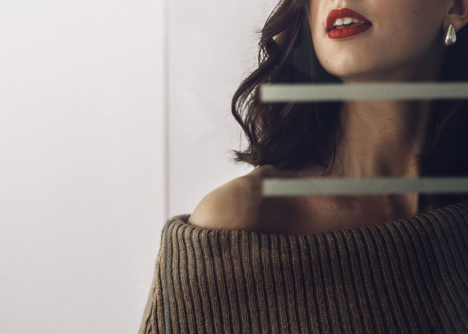 Artistic portrait showing off-shoulder brown sweater and red lipstick.