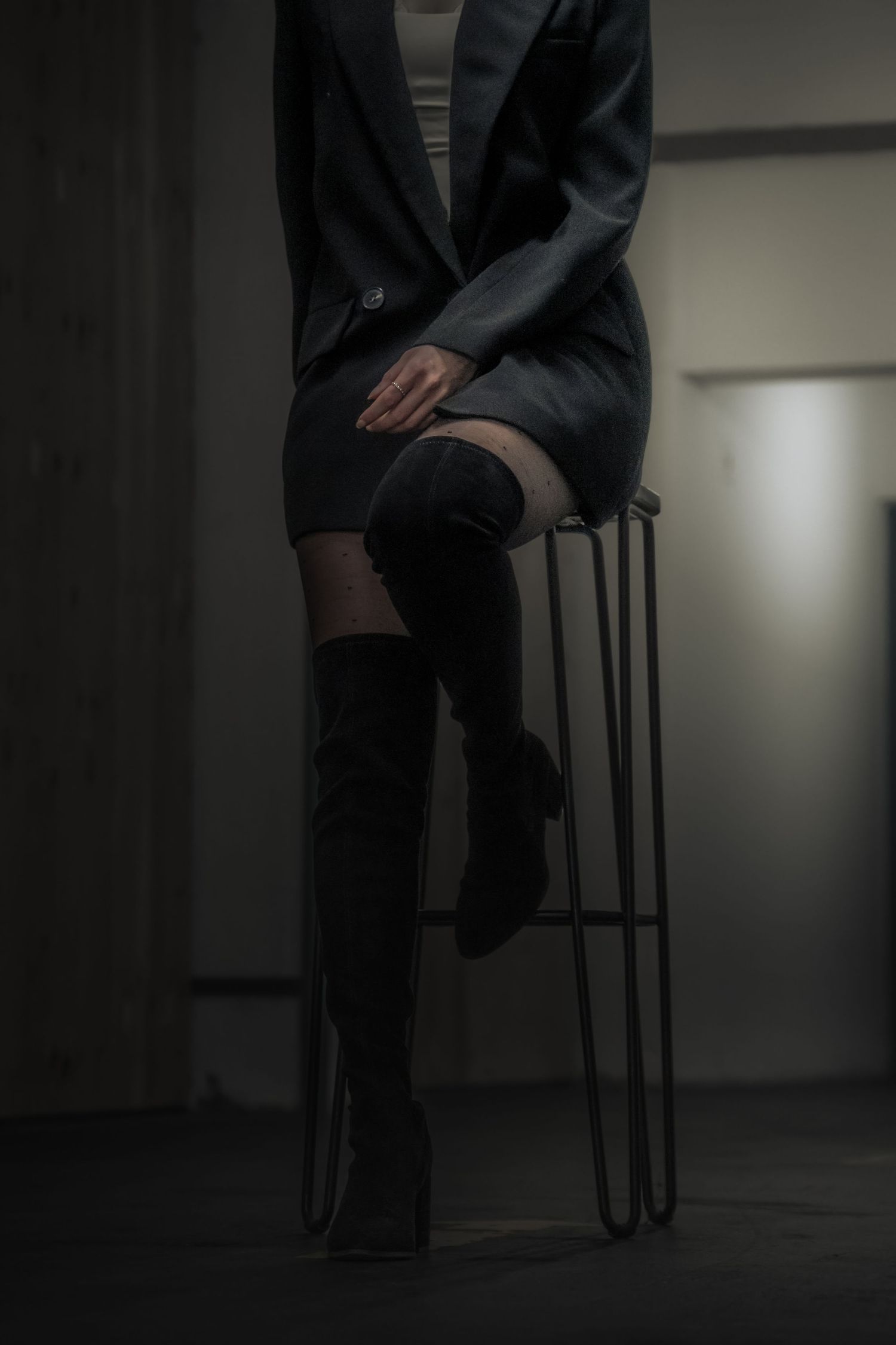 Silhouetted figure sitting on chair in dark moody lighting.