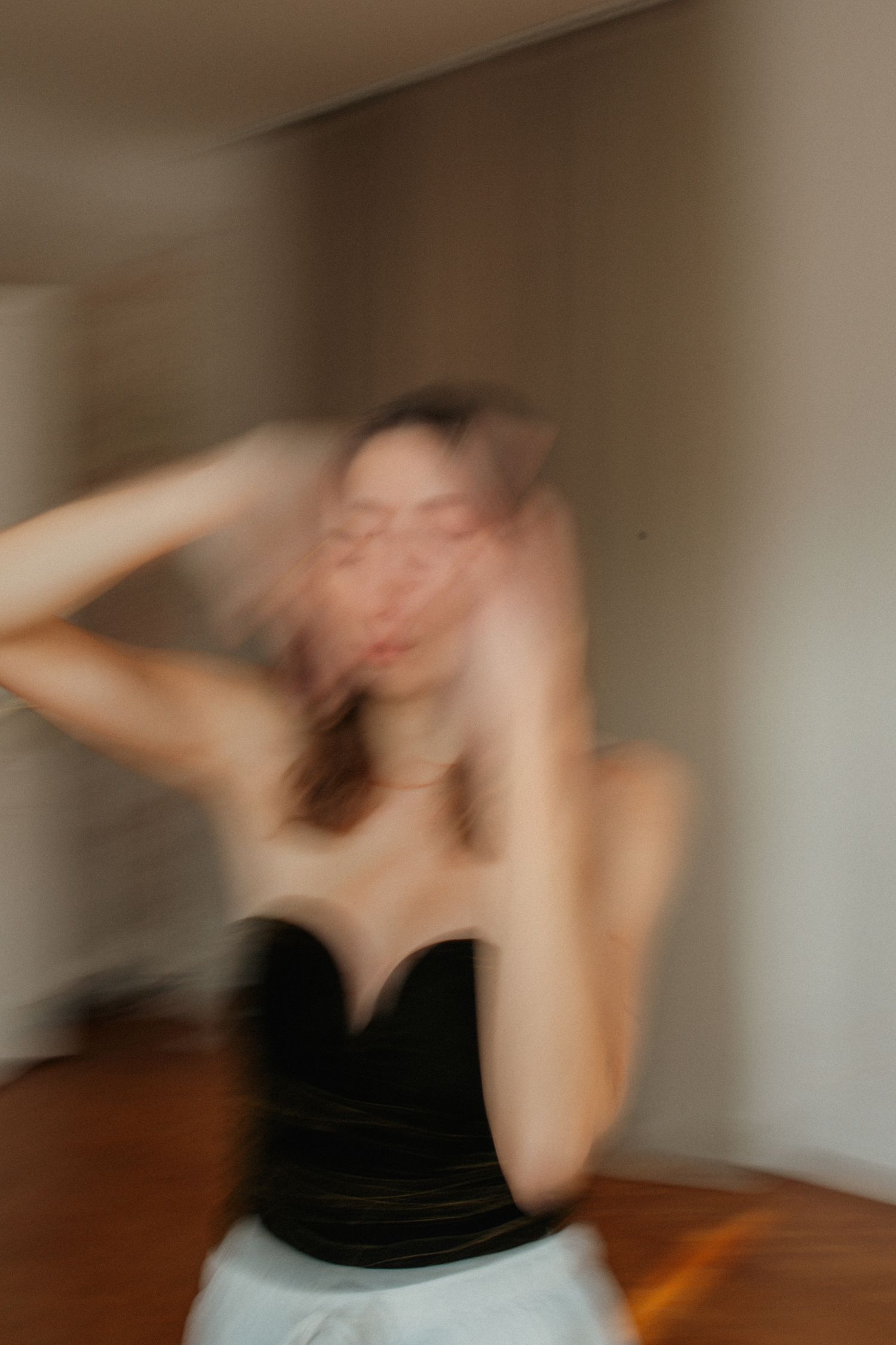 A blurred motion sequence shows a person in black clothing performing dance or movement poses against a white wall.